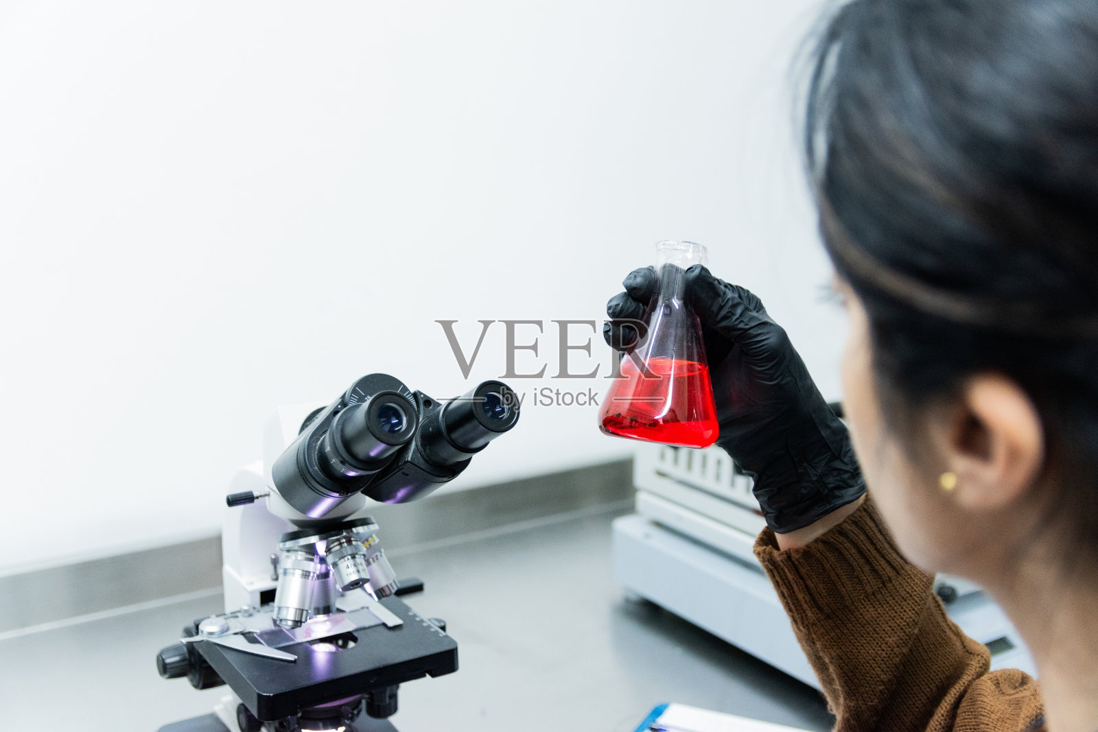 一个中年妇女在实验室里分析烧瓶的特写照片摄影图片