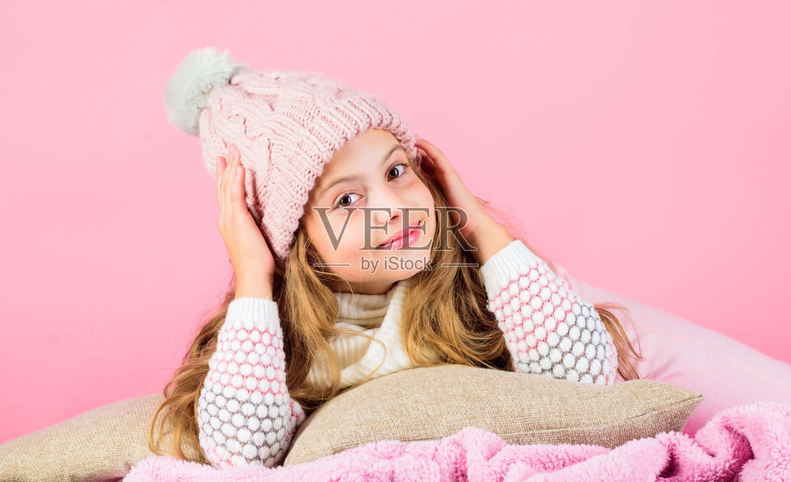 冬天休息放松。冬季概念。冬季时尚配饰。小女孩编织的帽子和围巾。冬季配饰概念。女孩长发梦粉色背景。孩子梦幻般的戴着针织帽照片摄影图片