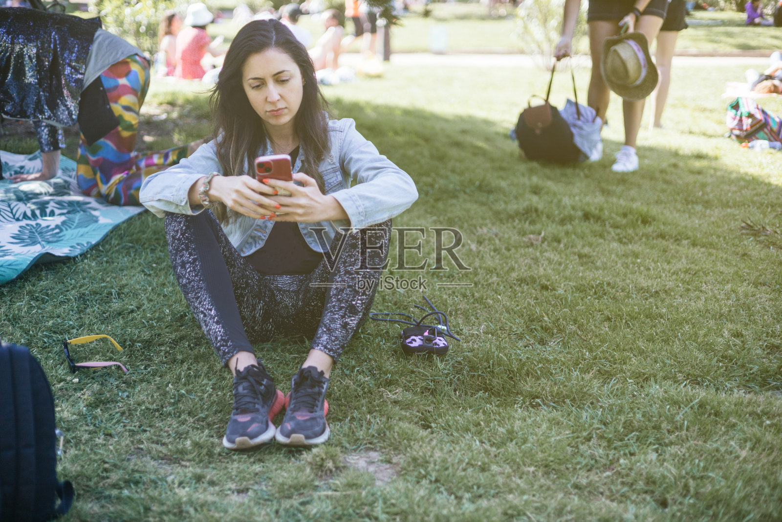 在一个满是露营者的夏季公园里，一个年轻的拉丁裔女子在音乐节上和朋友们发短信照片摄影图片
