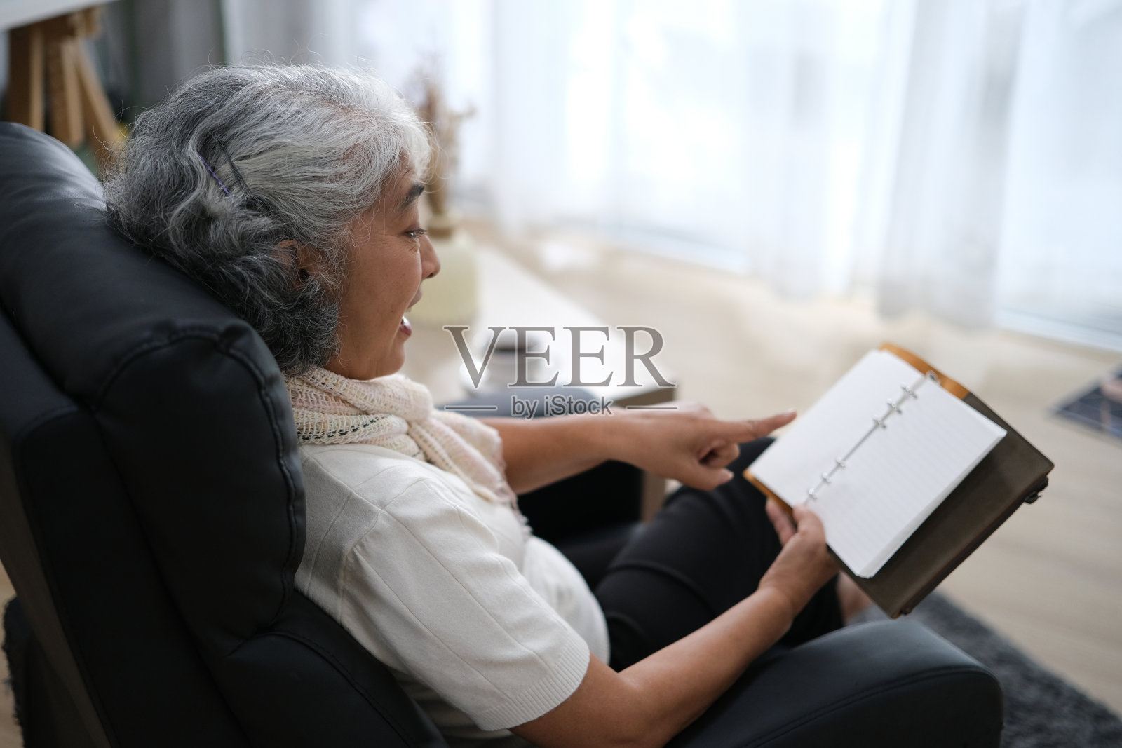 美丽放松的老年妇女坐在家里的扶手椅上看书的肖像照片摄影图片