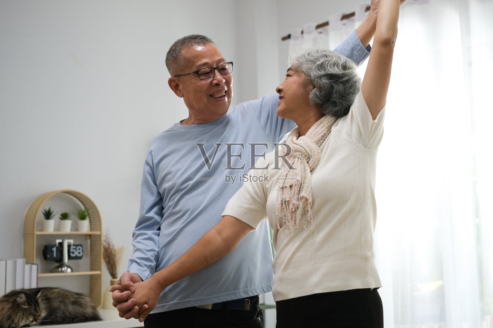 老年夫妇手拉手在客厅跳舞的选择性焦点照片摄影图片