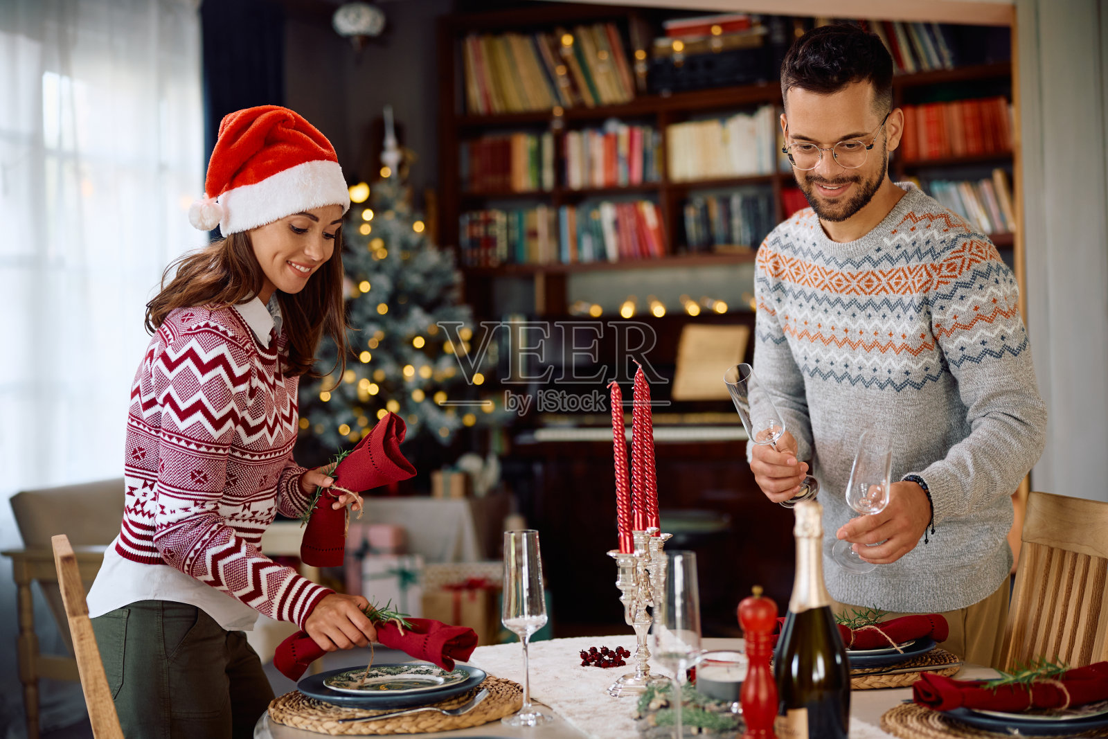 幸福的夫妇在为圣诞晚餐布置餐桌。照片摄影图片