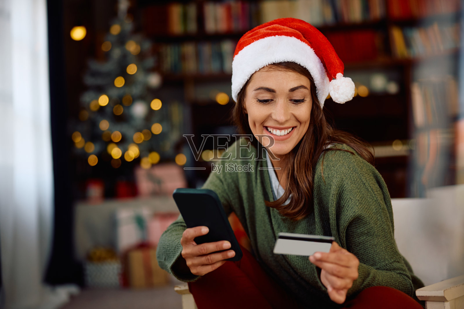 快乐的女人寒假在家用手机和信用卡做移动银行。照片摄影图片