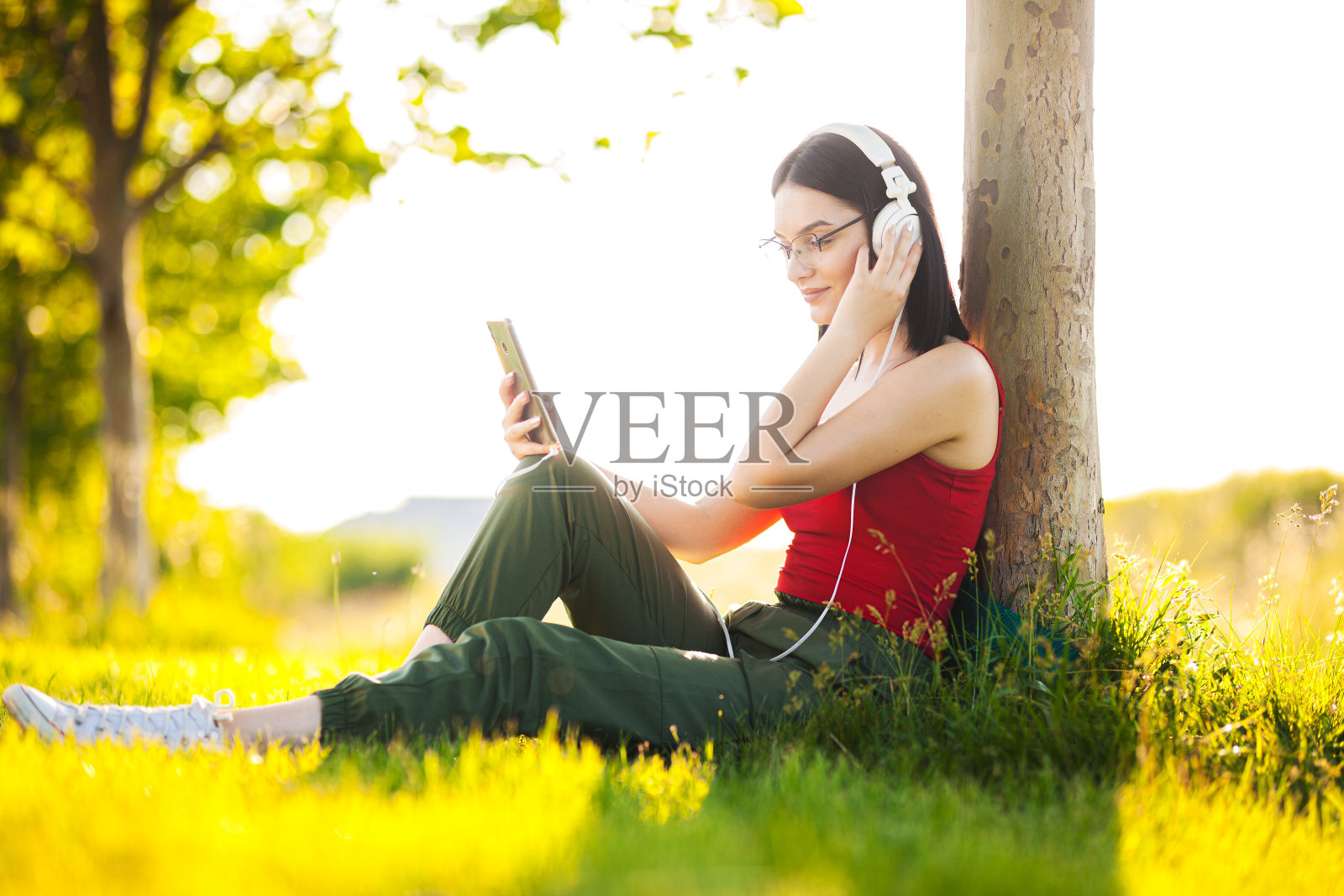 黑发女孩用智能手机戴着耳机听音乐照片摄影图片