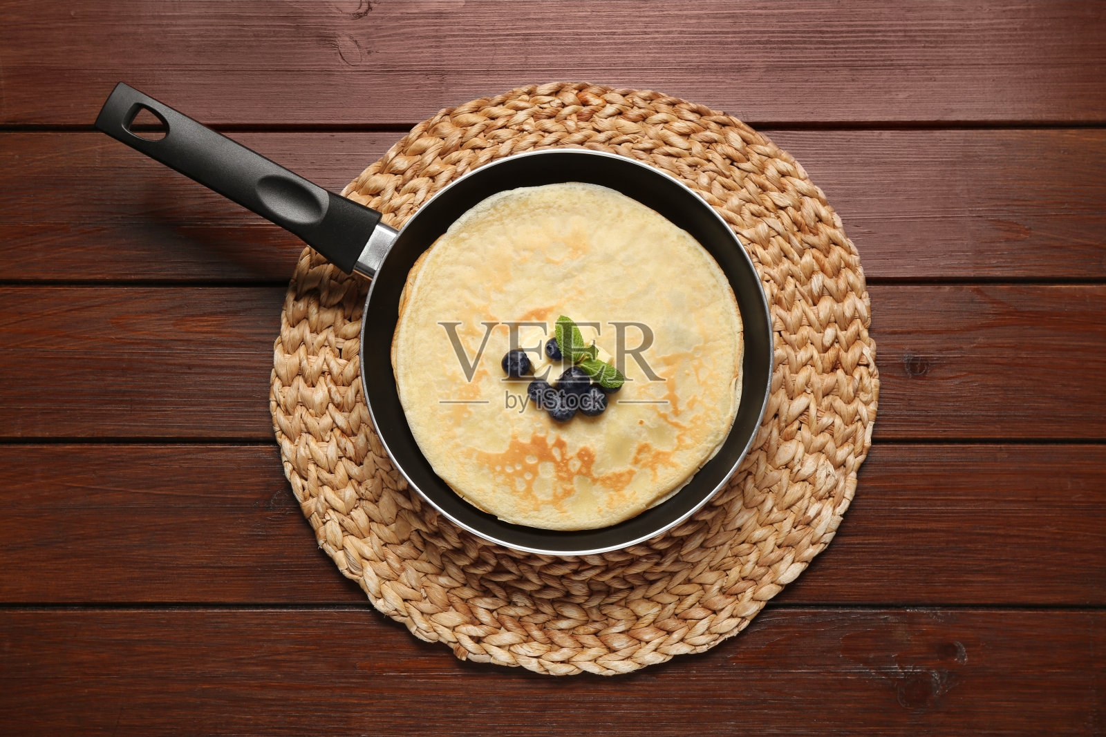 美味的可丽饼配上新鲜的浆果，融化的黄油和薄荷放在木桌上，俯视图照片摄影图片