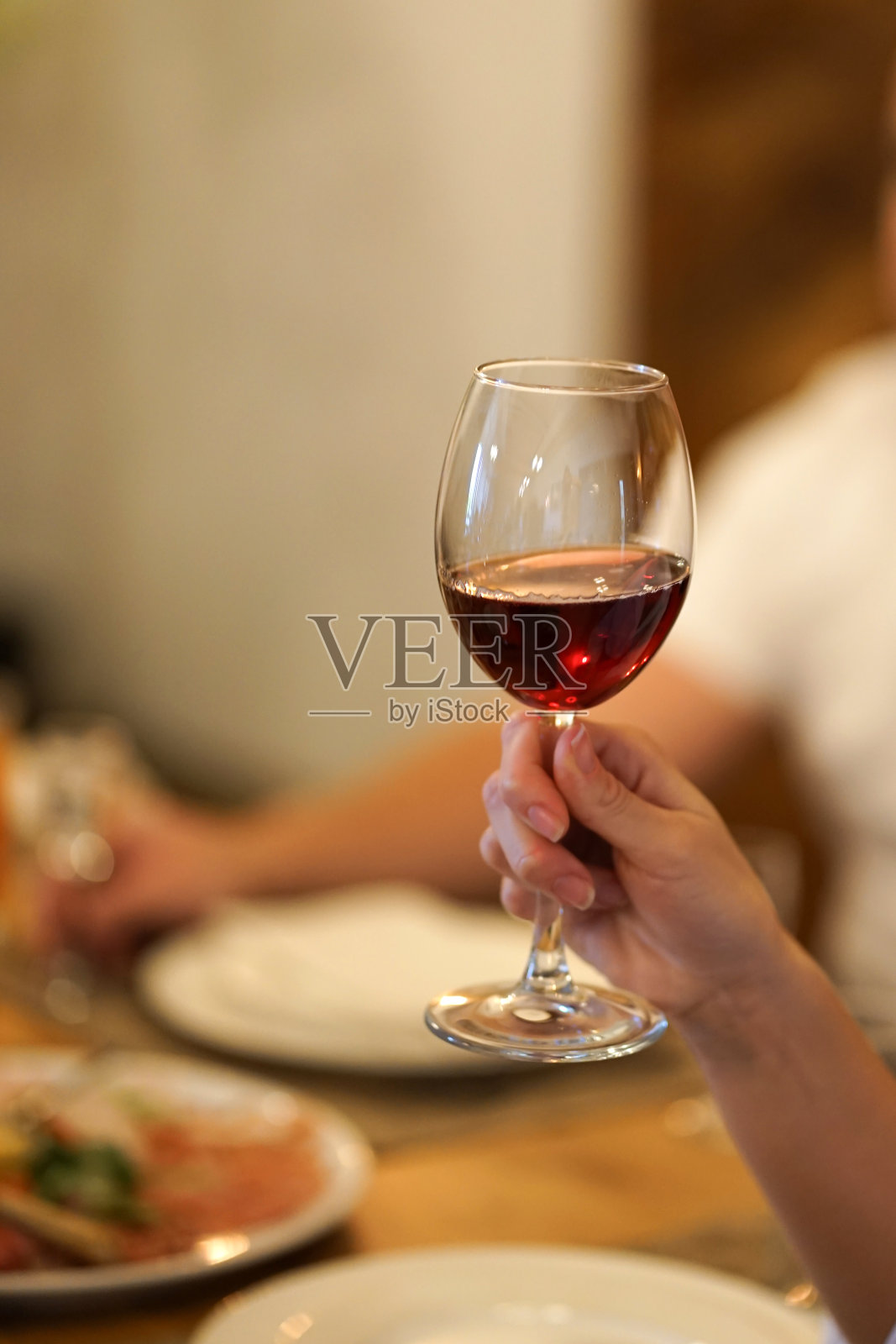 一位女士在宴会上举起一杯红酒。照片摄影图片