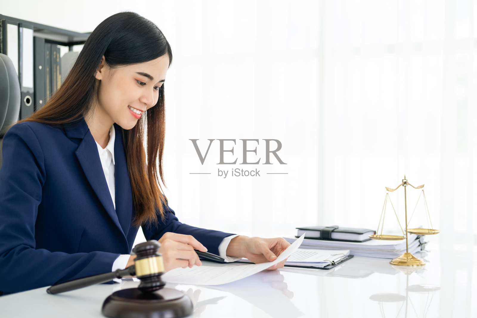 现代办公室里的女律师，白色桌子上有黄铜天平和木槌。正义与法律概念照片摄影图片