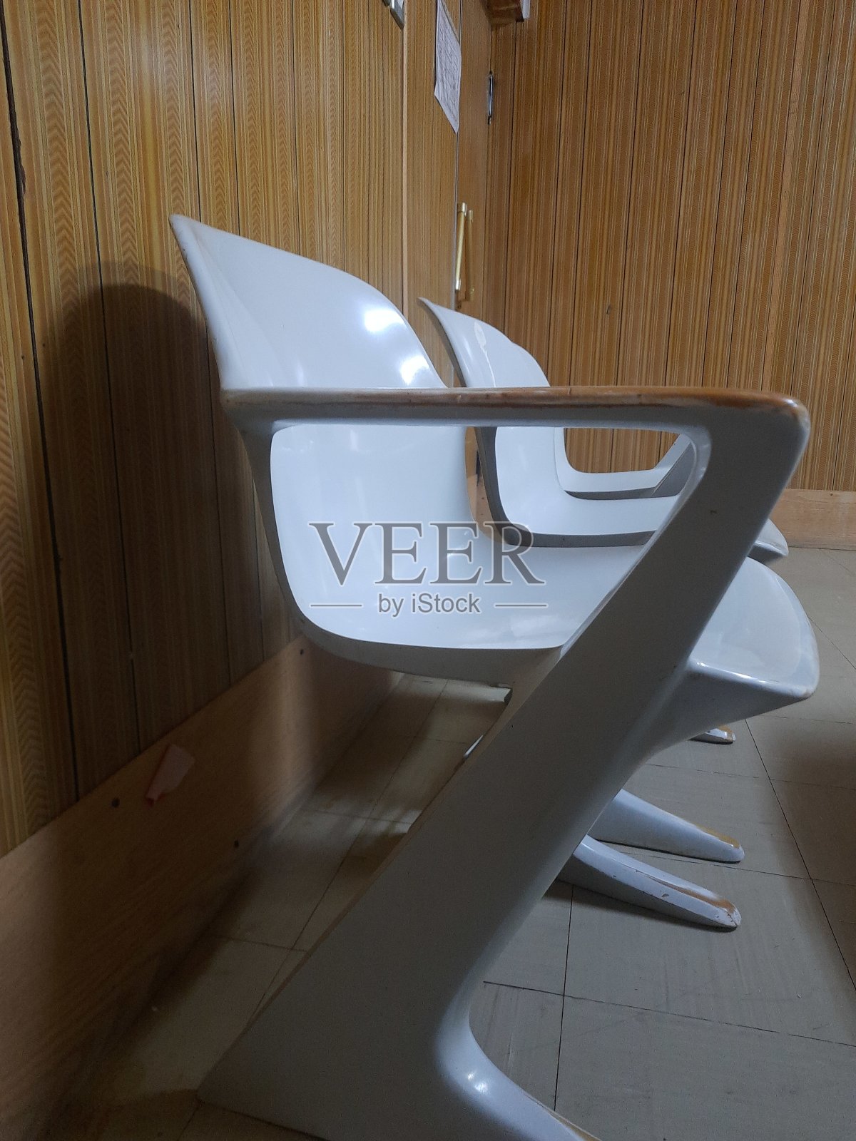 办公室家具，三把旧塑料椅子，具有未来主义风格，位于 20 世纪 70 年代风格的墙前照片摄影图片