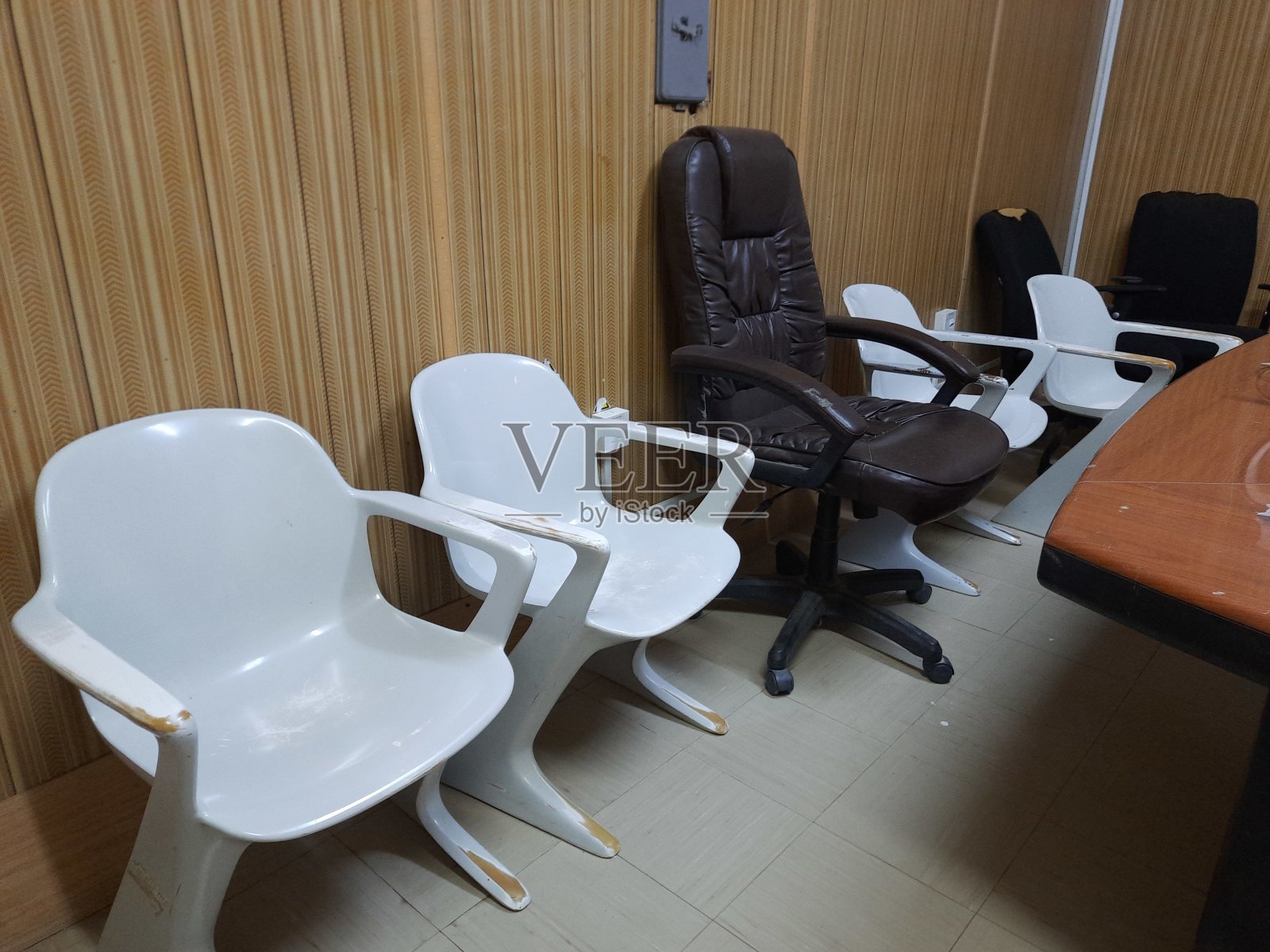 办公室家具，围绕着老板的座位，一张豪华的棕色皮椅周围是四张白色塑料椅子照片摄影图片