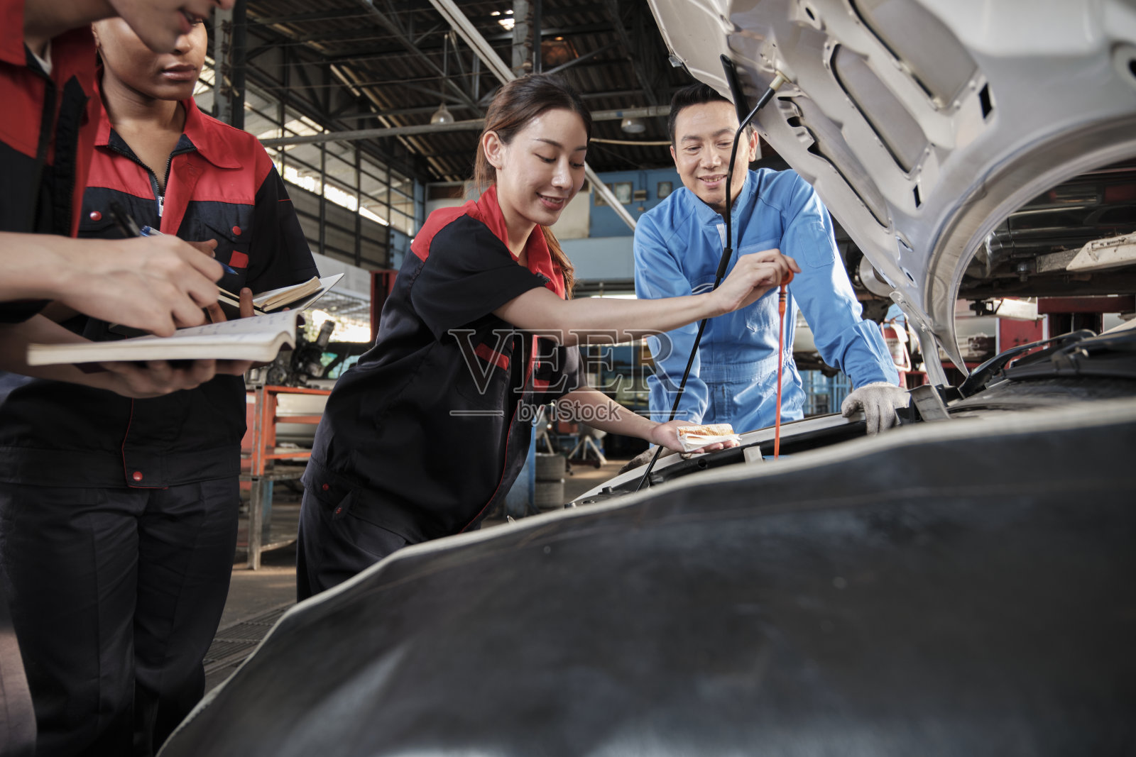 一位男性汽车主管在汽车修理厂指导机械工人队伍。照片摄影图片