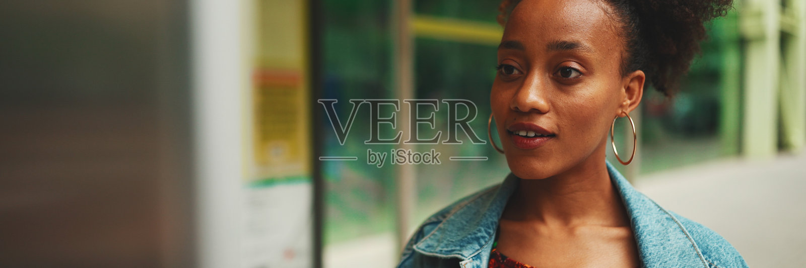 可爱的非洲女孩扎着马尾辫，穿着牛仔夹克，穿着民族图案的露脐上衣，站在公交车站微笑照片摄影图片