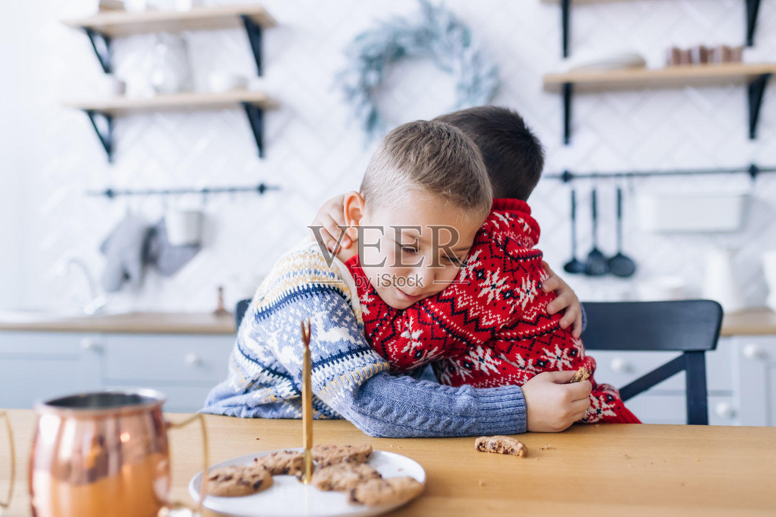 小弟弟们坐在桌子旁拥抱，吃饼干。照片摄影图片