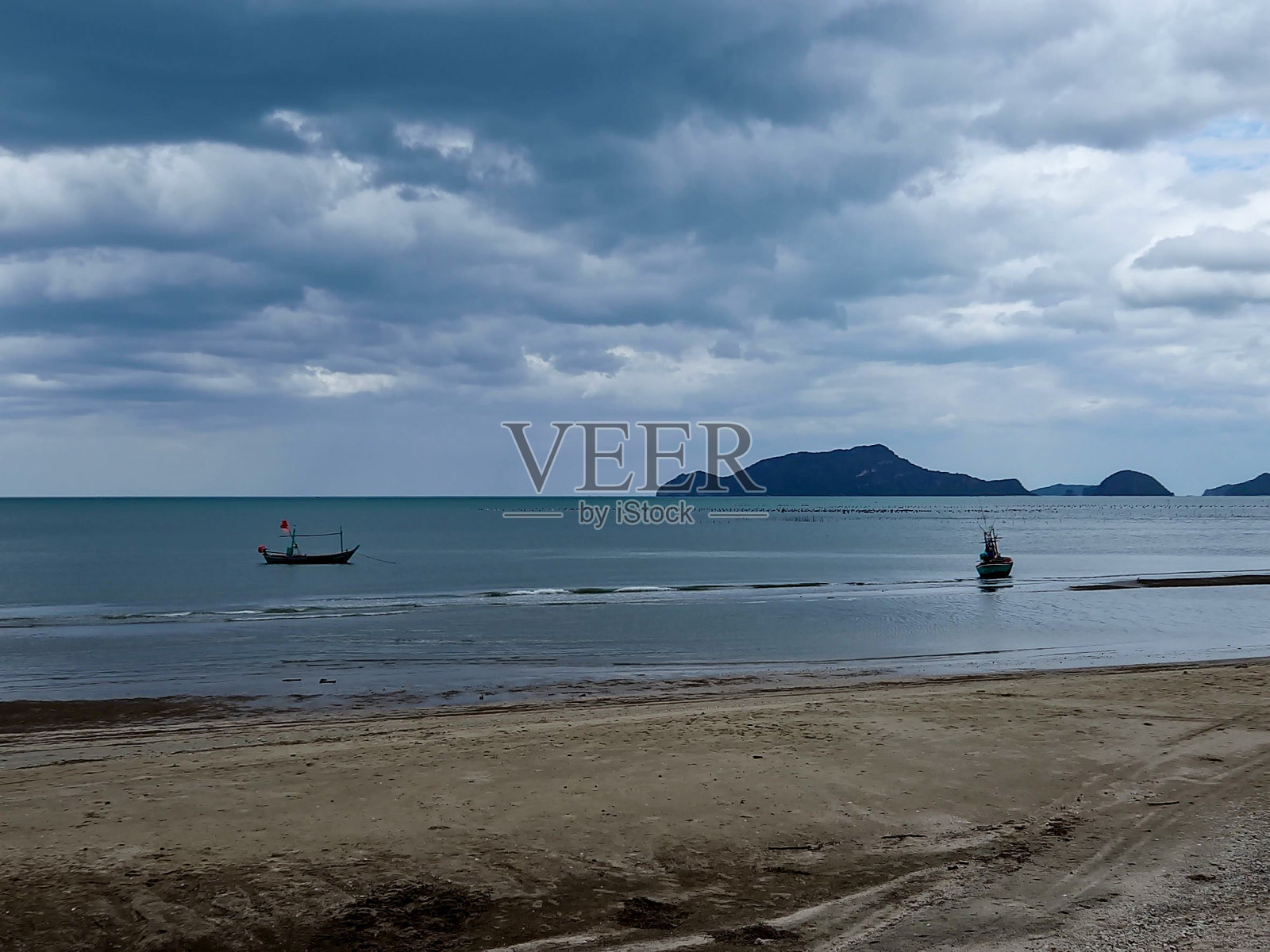 海滩与深蓝色的海洋和云地平线与渔船从远处看照片摄影图片