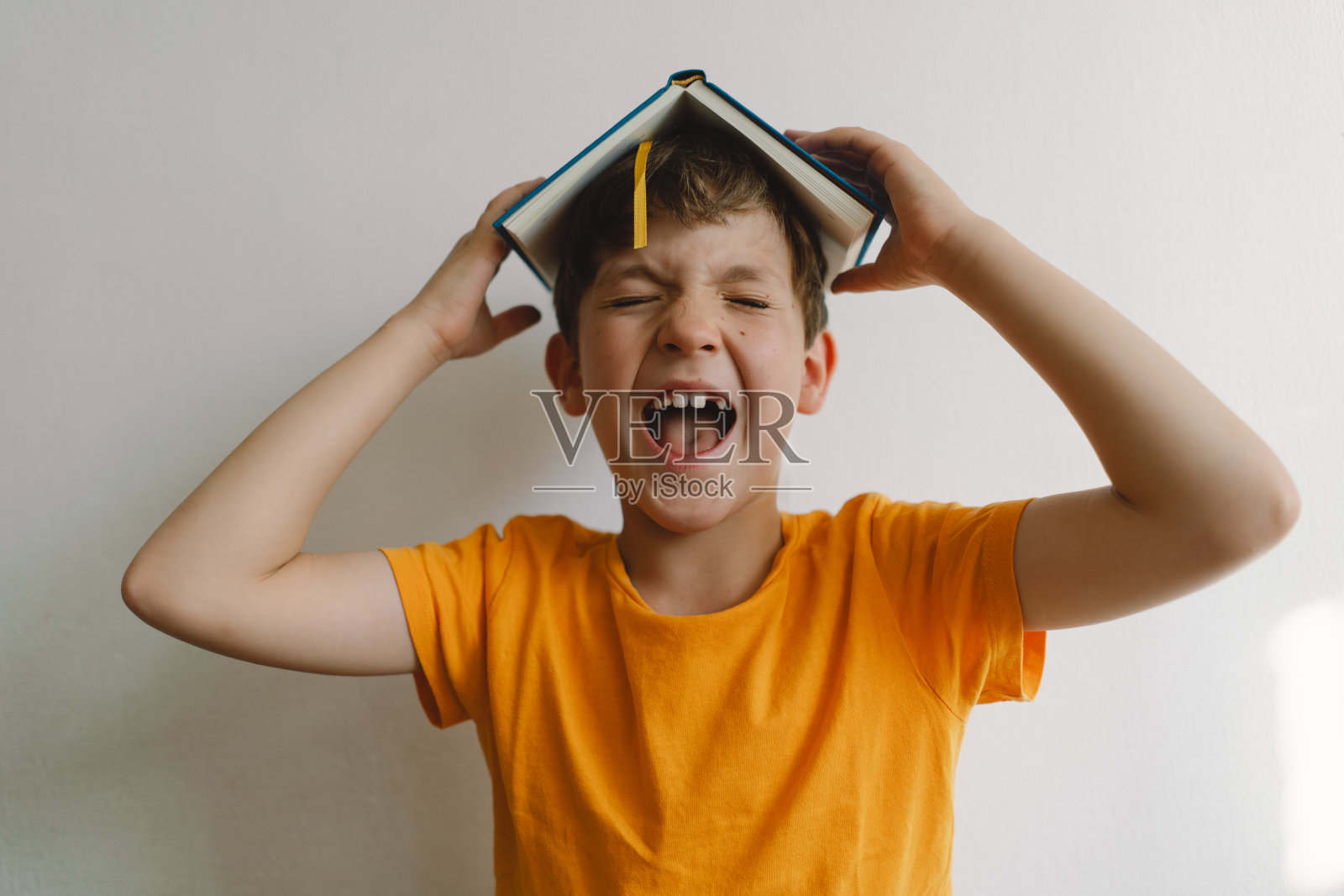 一个可爱的男孩正坐在柔软的软垫上看书。照片摄影图片