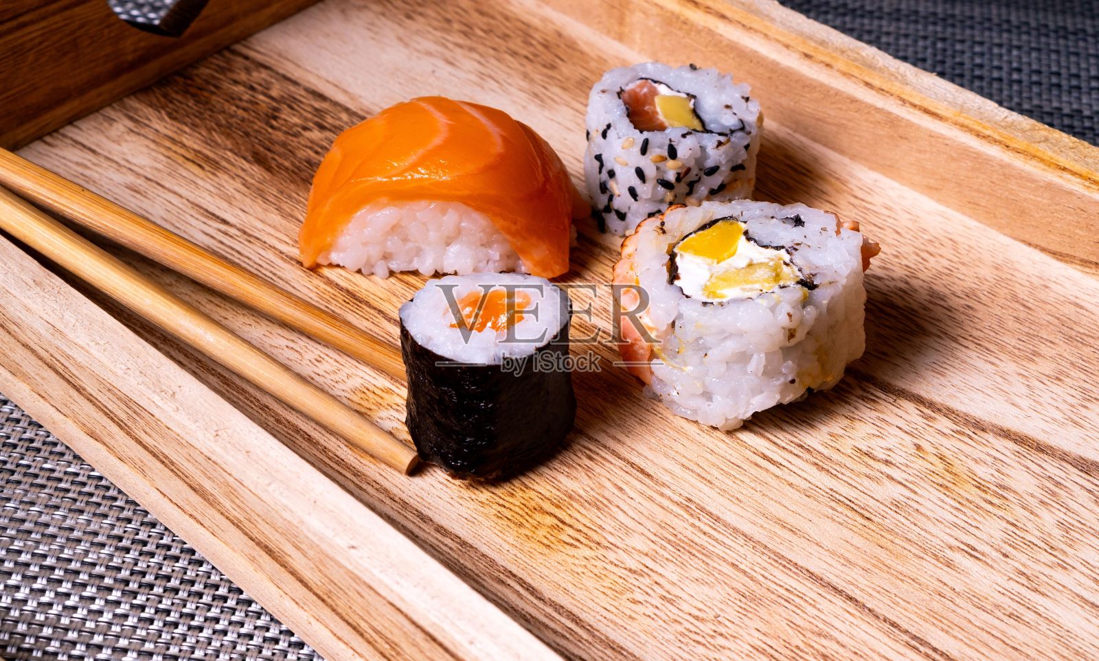 木制托盘，上面放着四张寿司卷和筷子照片摄影图片