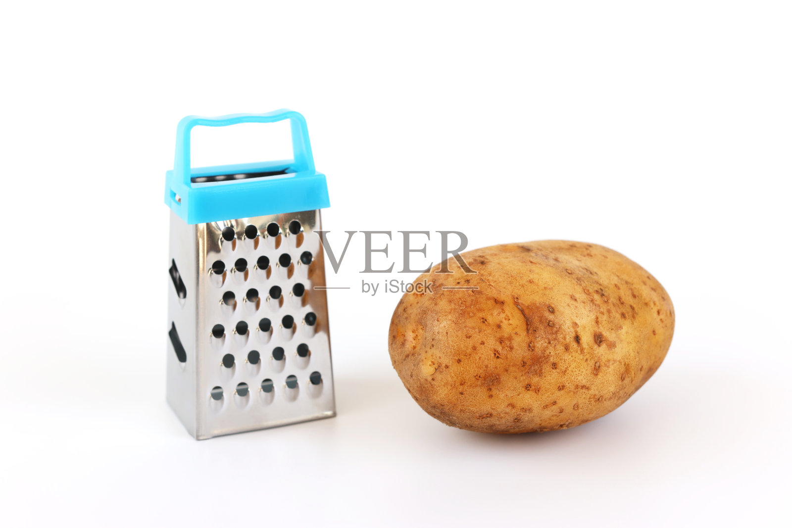 手工制作的微型磨碎器和生的未削皮土豆在白色的背景。照片摄影图片