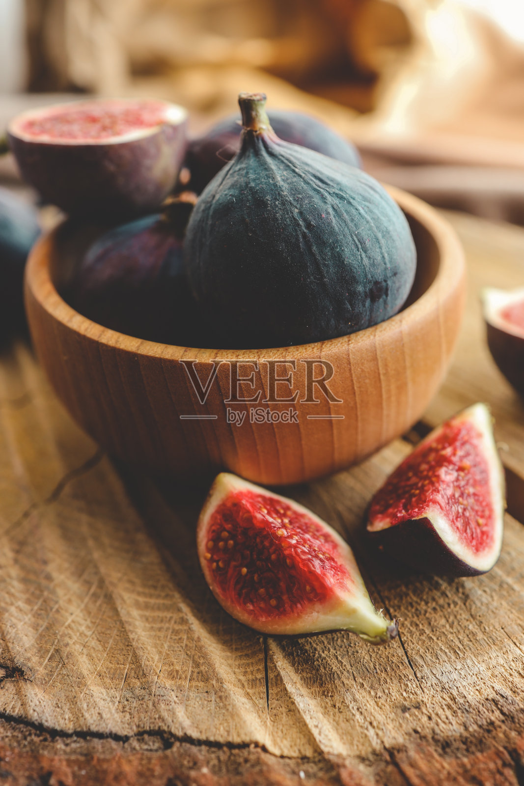 在一个古老的木制背景上，碗里放着几颗无花果。照片摄影图片