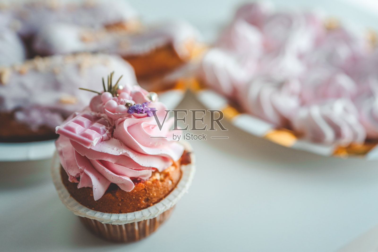 香草蛋糕与奶油芝士糖霜和粉红色的洒在粉红色的背景。情人节或生日甜点照片摄影图片