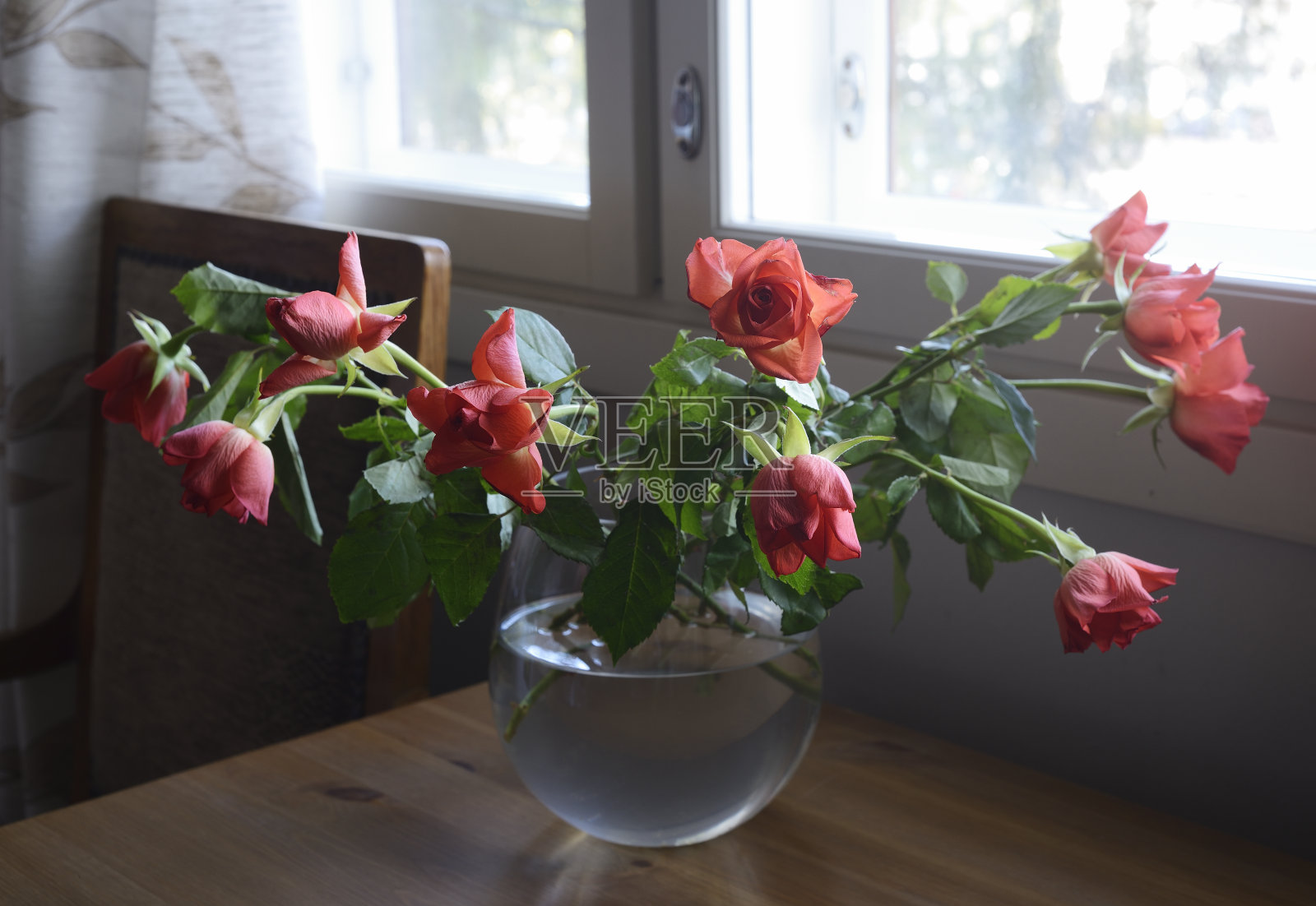 木桌上的玻璃花瓶里插着玫瑰花照片摄影图片
