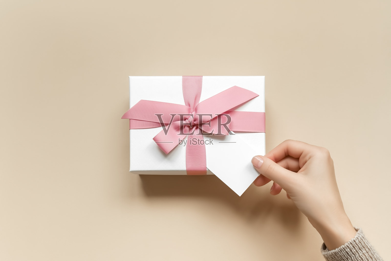 一位女士正在往礼品盒里加贺卡。母亲节、情人节、圣诞节和新年送礼概念照片摄影图片