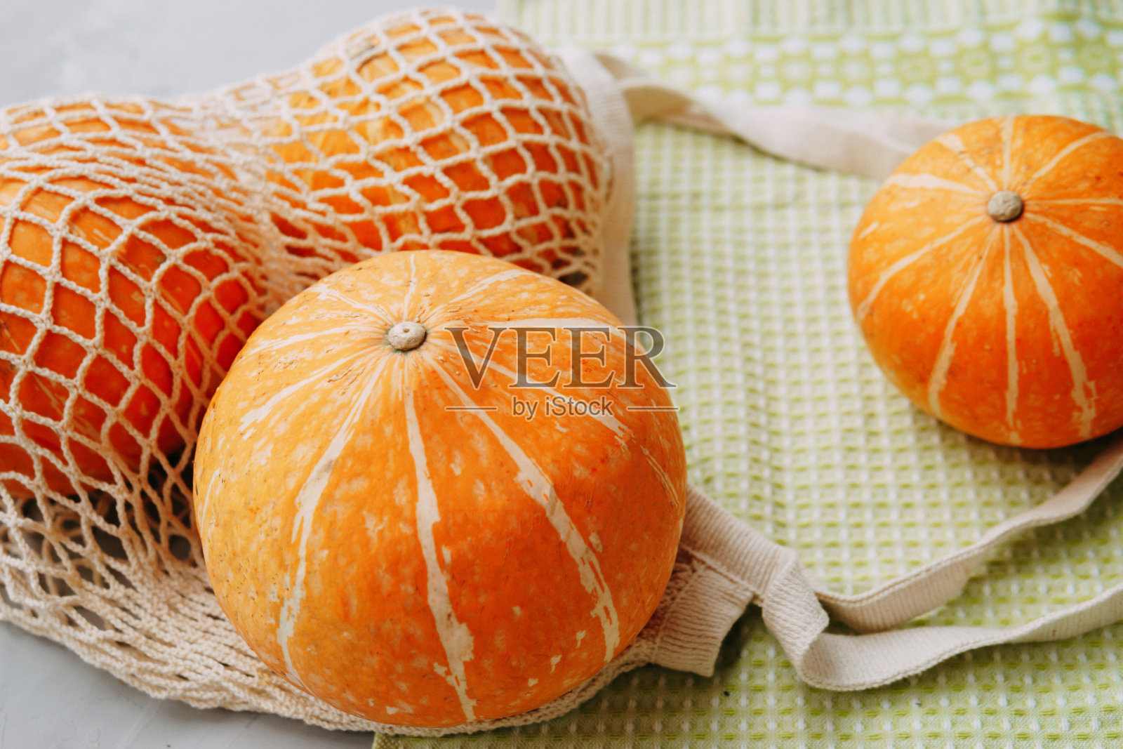 装有蔬菜的网状购物袋。南瓜秋收照片摄影图片