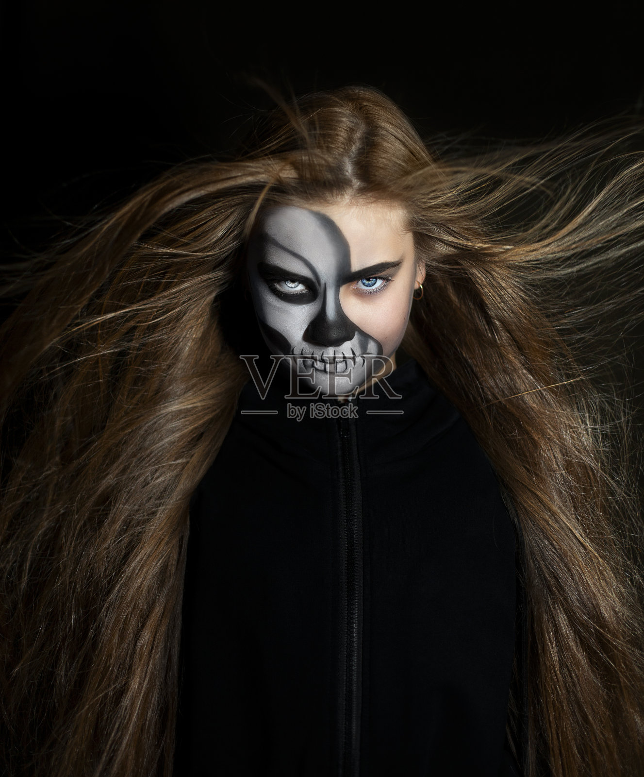 一个女孩的肖像与黑色骷髅妆在黑暗的背景。万圣节的概念照片摄影图片