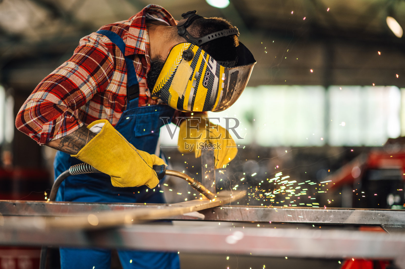 工厂里的工人小心翼翼地用焊机焊接金属。照片摄影图片