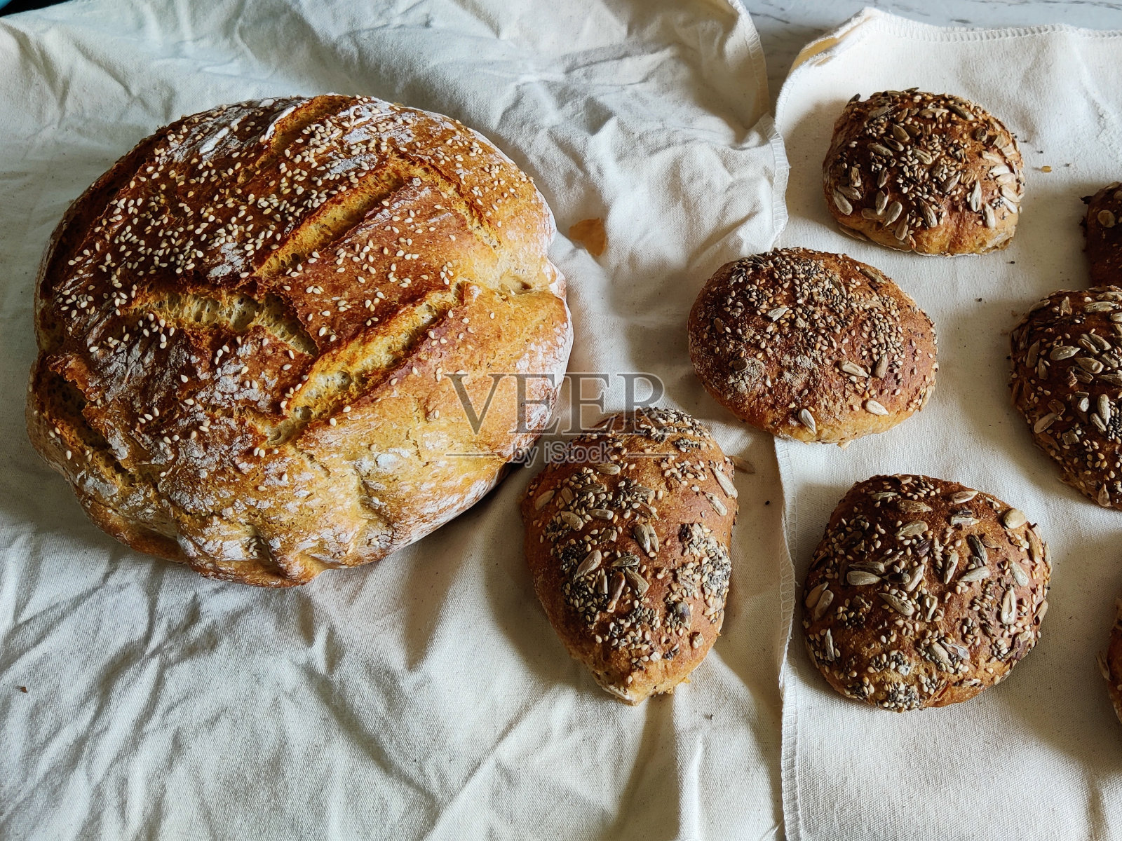 自制的小麦面包，加芝麻和一些全麦面包卷，放在面包铺的亚麻毛巾上照片摄影图片