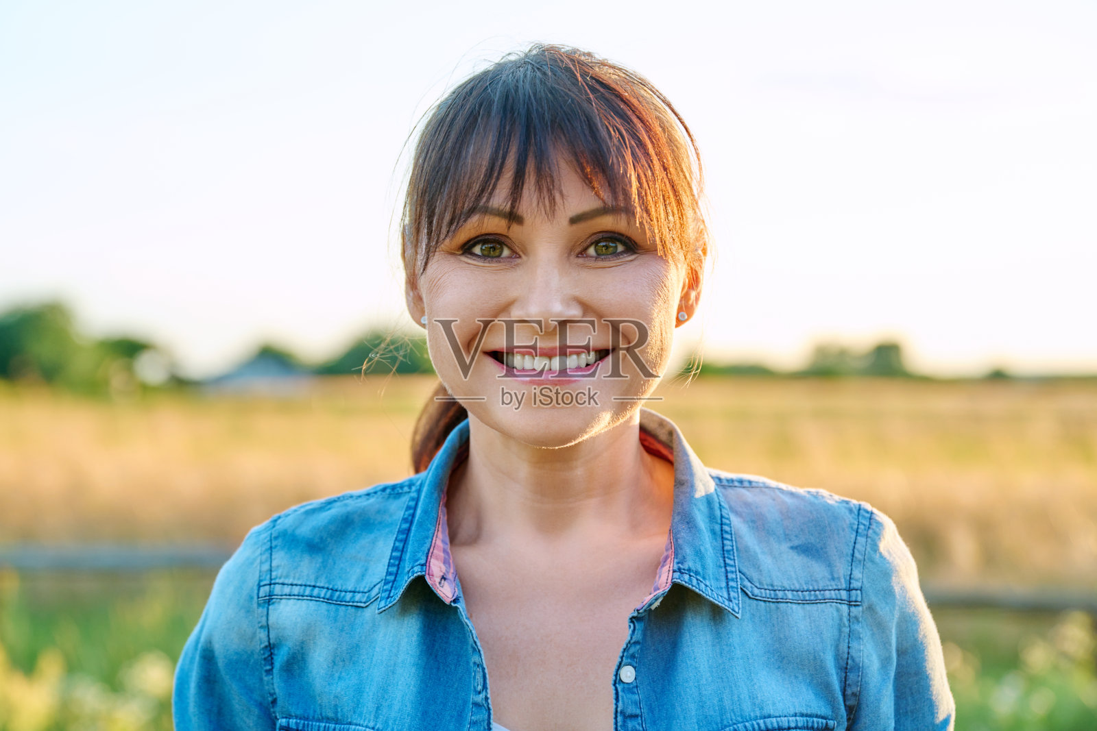 夏日乡村，中年妇女看着相机微笑的肖像照片摄影图片