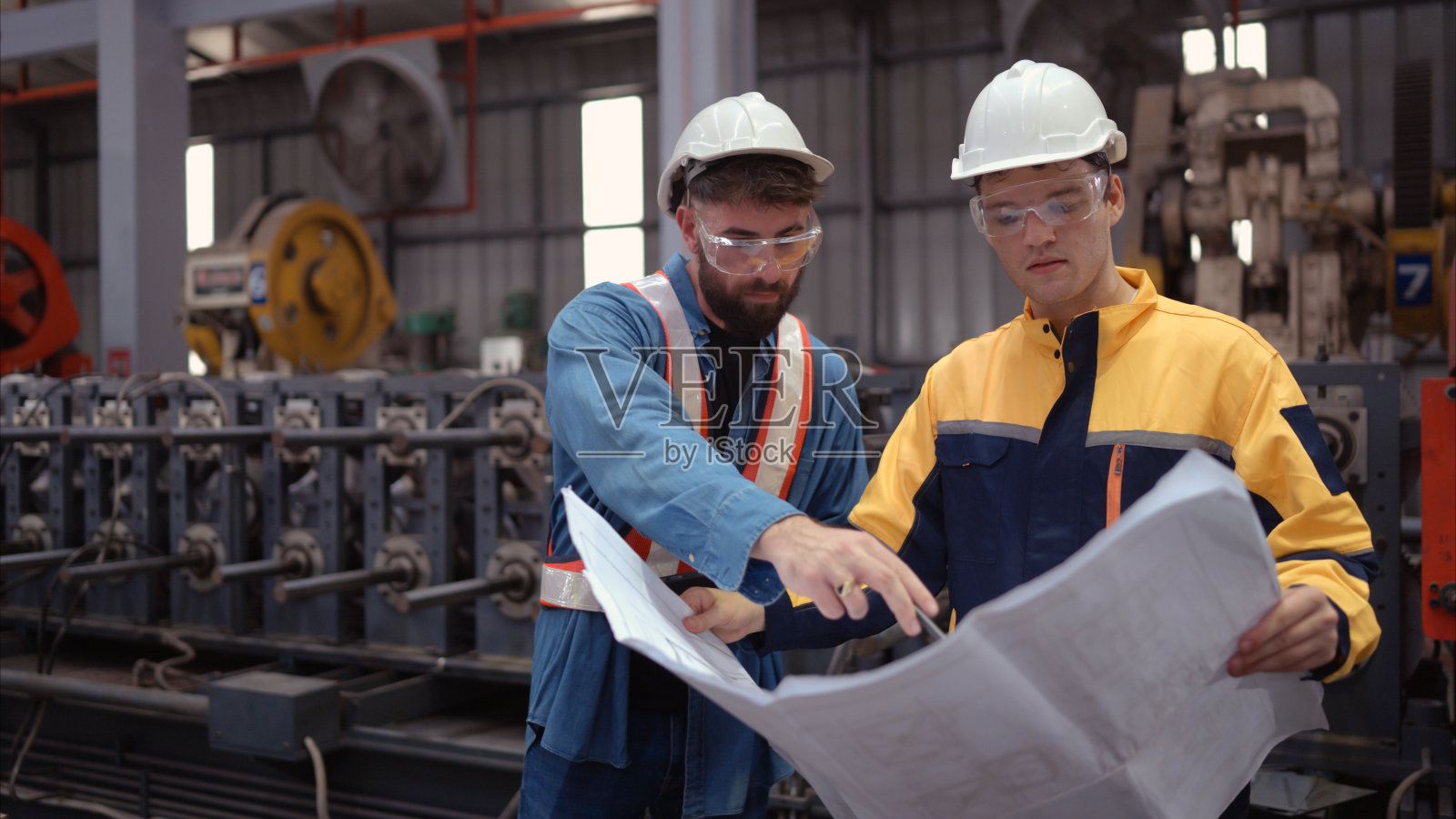 工程师和建筑师团队在工厂现场设计图纸。这是一个大型的新设施，用于制造金属板材以及运输和配送仓库。照片摄影图片
