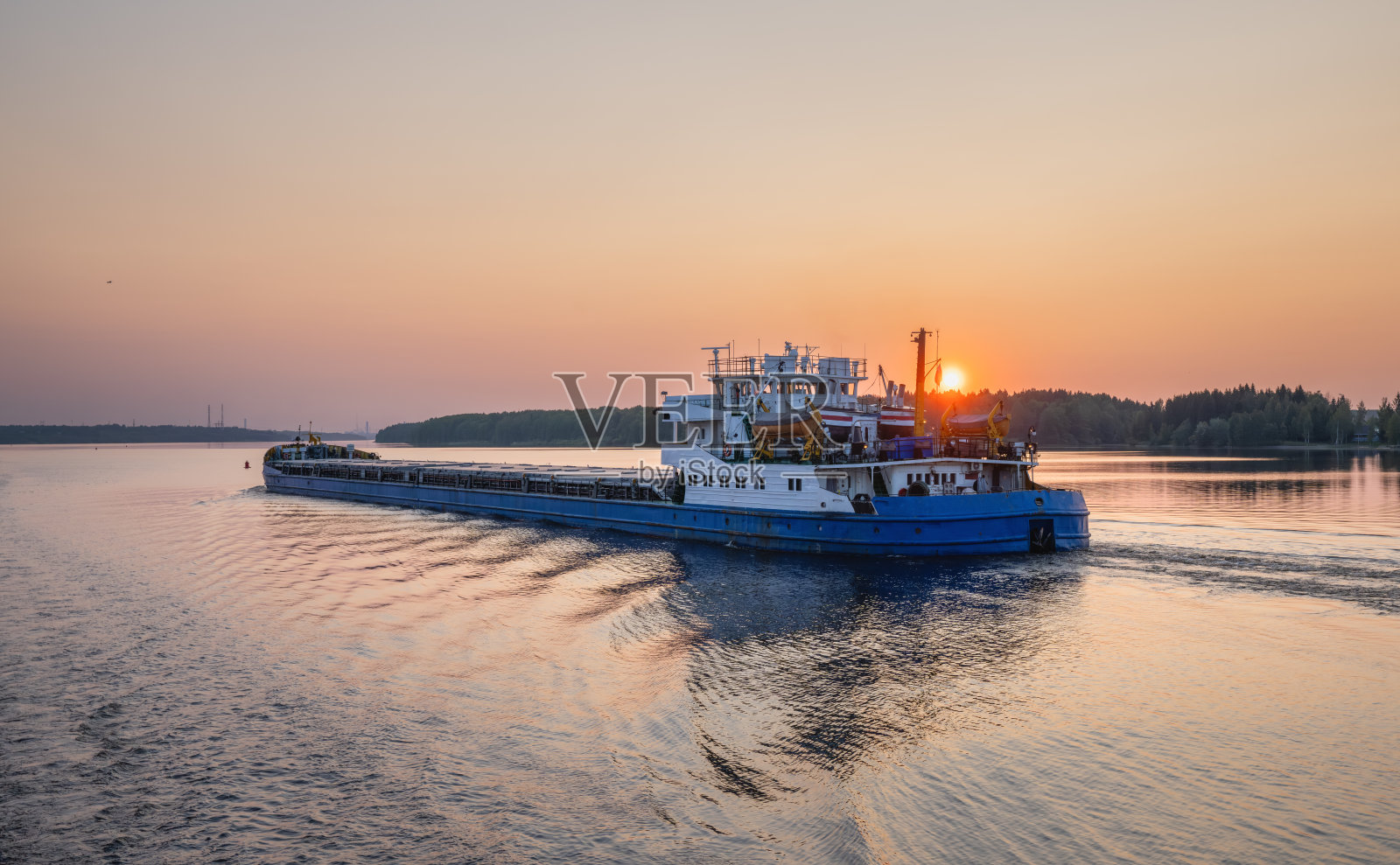 一艘驳船漂浮在伏尔加河上，背景是日落照片摄影图片