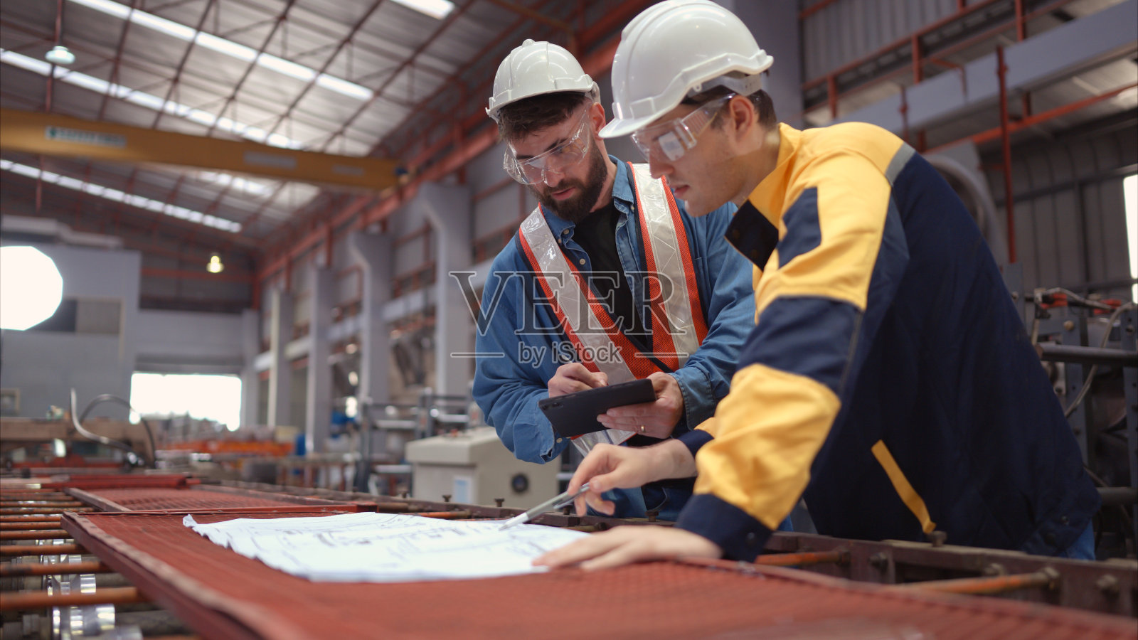 工程师和建筑师团队在工厂现场设计图纸。这是一个大型的新设施，用于制造金属板材以及运输和配送仓库。照片摄影图片