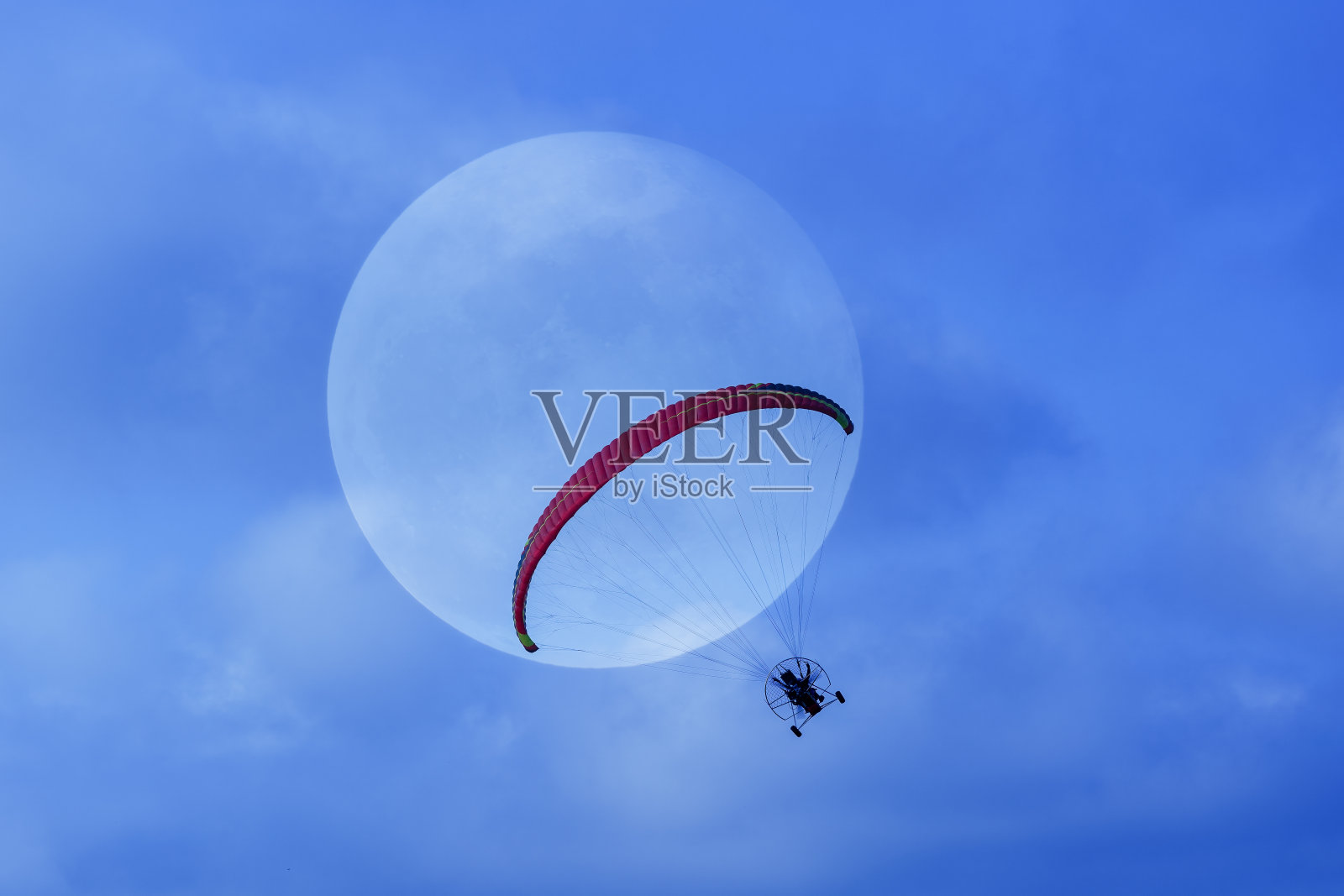 一个人在月球前驾驶摩托车飞行。照片摄影图片