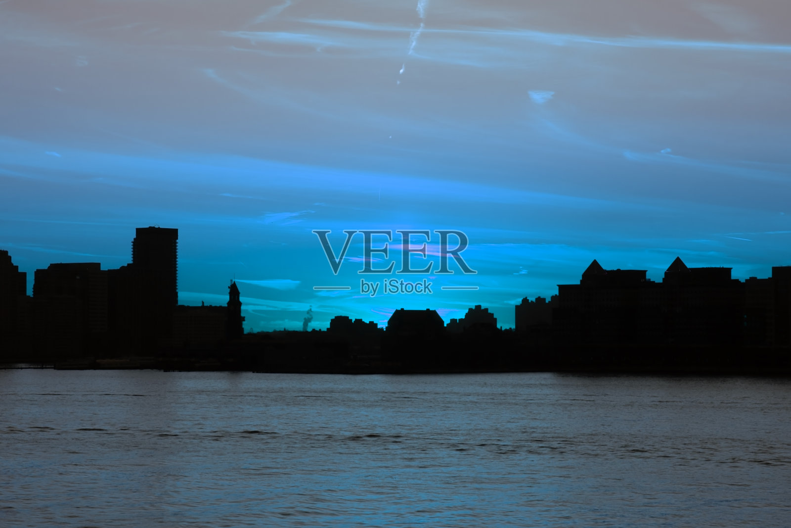 曼哈顿的摩天大楼在日落时分从水面上远眺，纽约的现代建筑景观从海滨远眺照片摄影图片