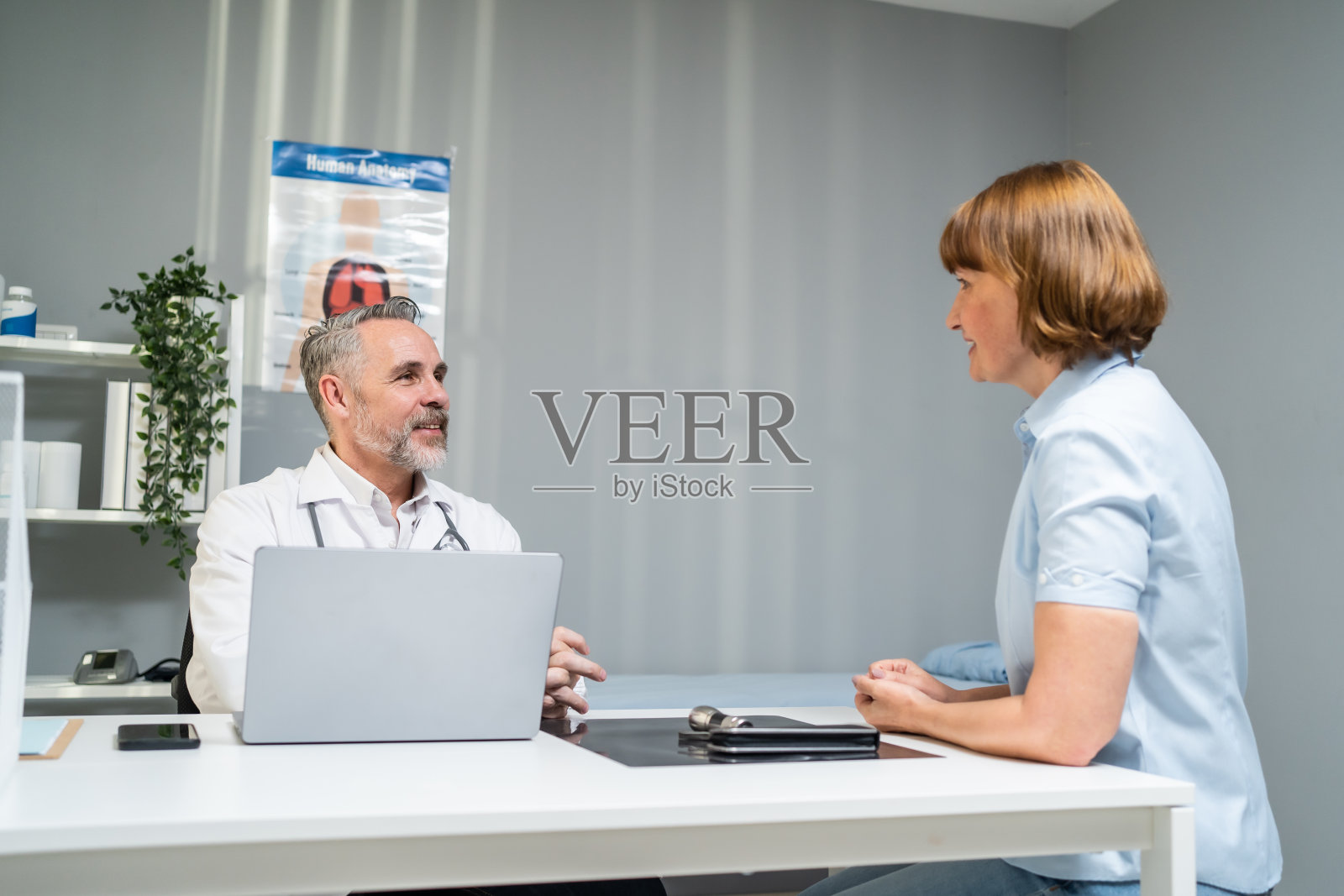 白人老年妇女向医生咨询健康问题。在医院预约期间向患病妇女解释诊断和给予治疗的成熟老年治疗师。照片摄影图片