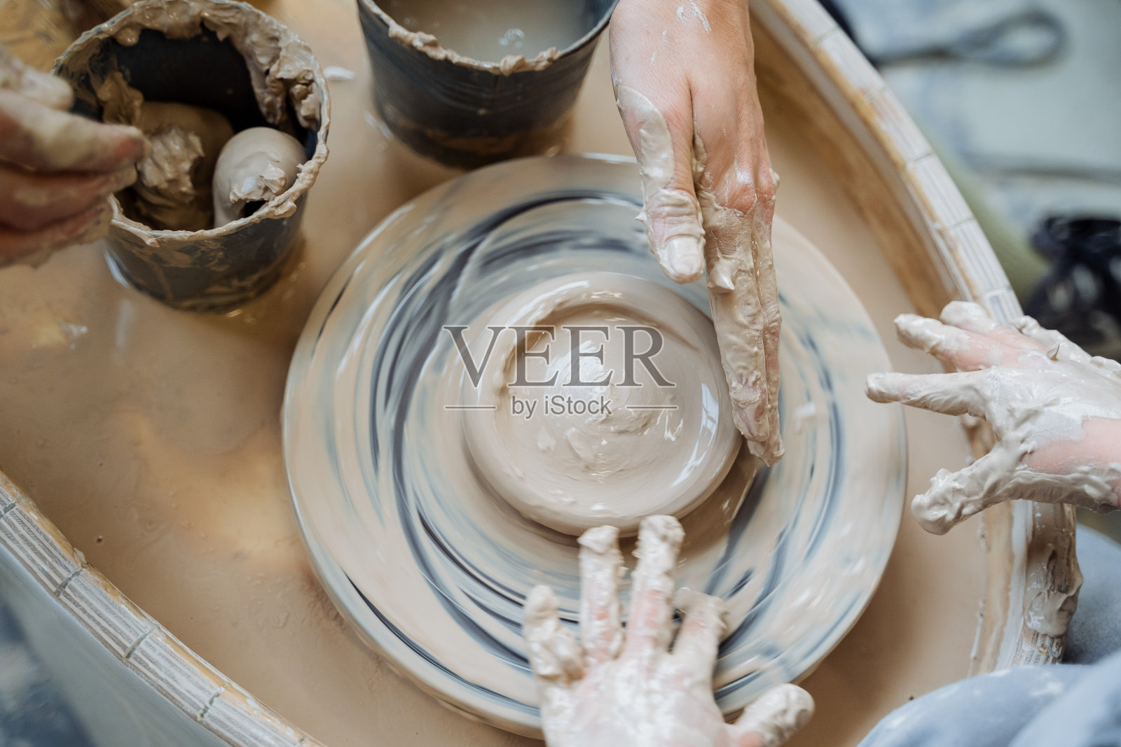 这孩子正在做陶工的转盘。陶器作坊。陶罐造型。儿童创意。手部的精细运动技能。四手。照片摄影图片