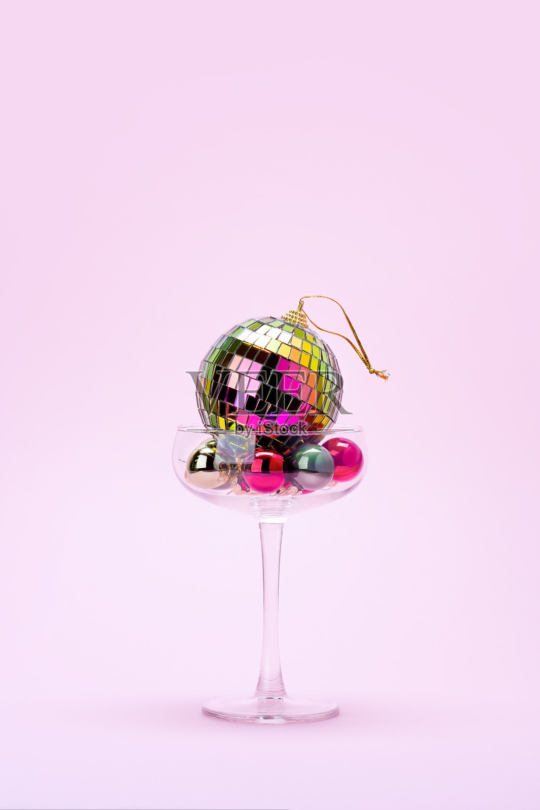 淡粉色背景上的鸡尾酒杯和圣诞装饰。照片摄影图片