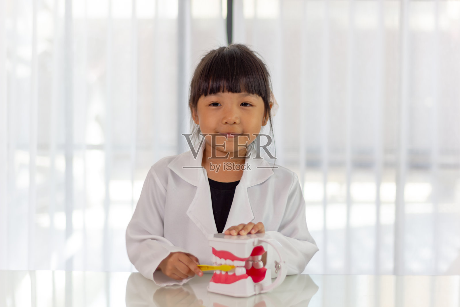 可爱有趣的小女孩拿着牙颌和牙刷。儿童口腔卫生训练。孩子学习刷牙、清洁牙齿。预防儿童龋齿。儿童牙科。牙科护理儿童照片摄影图片