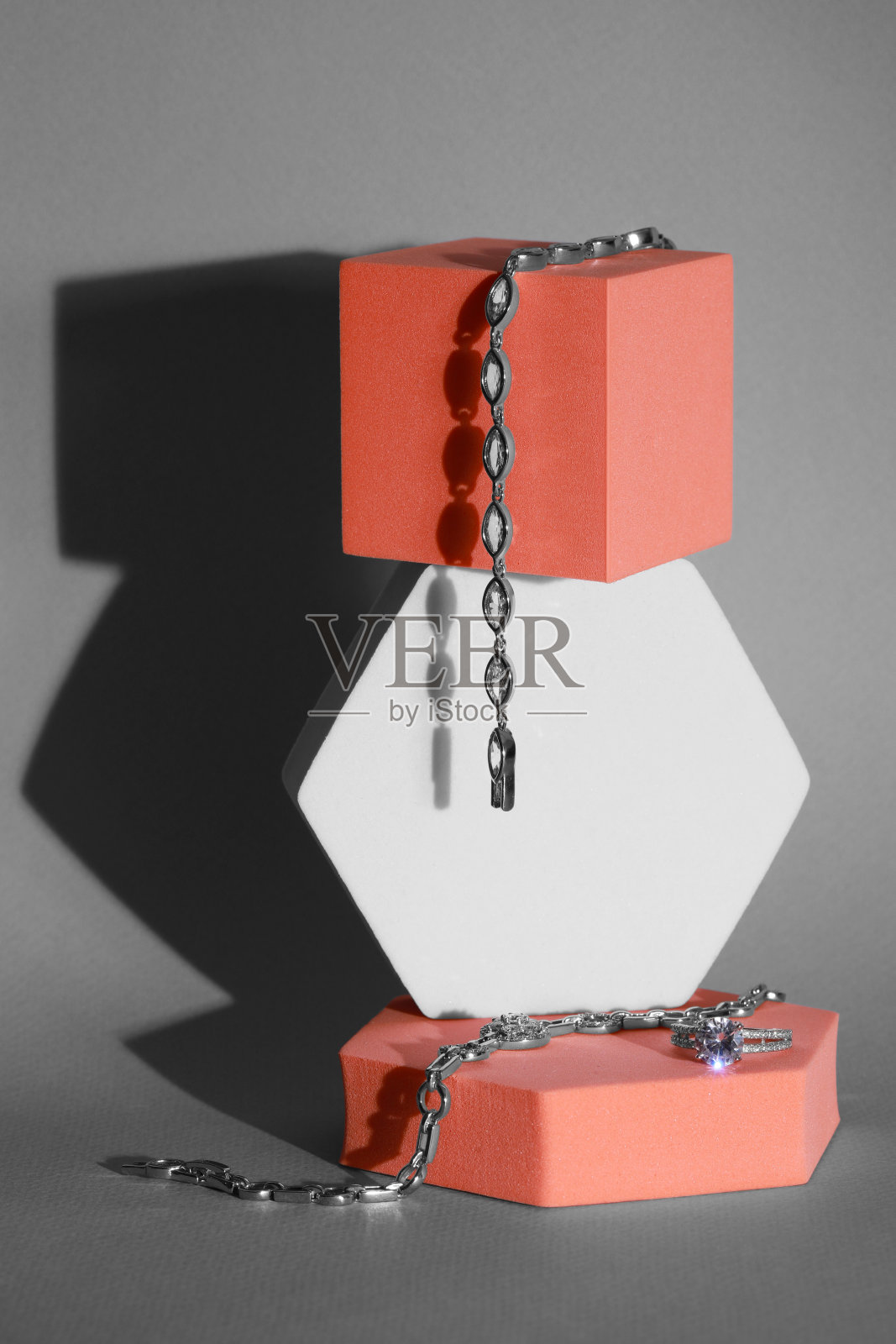 优雅的珠宝。奢华的手镯和戒指在灰色背景下的领奖台上的时尚展示照片摄影图片