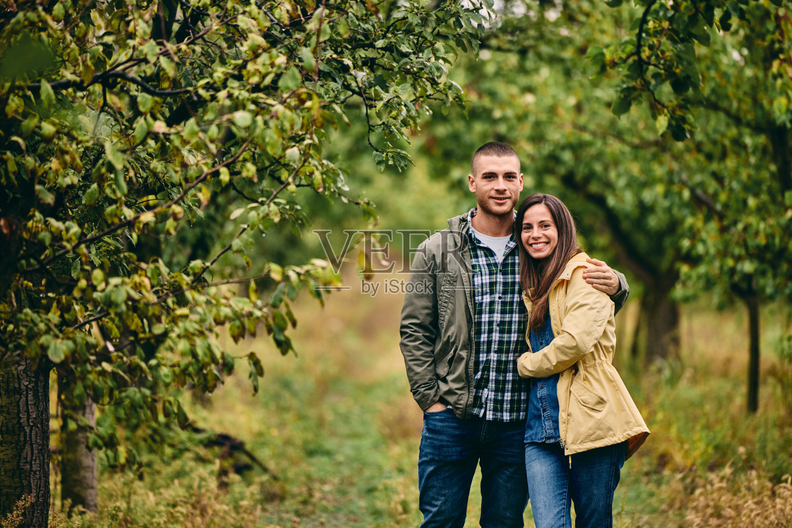 一对微笑的夫妇，站在一起，在大自然中为相机摆姿势。照片摄影图片