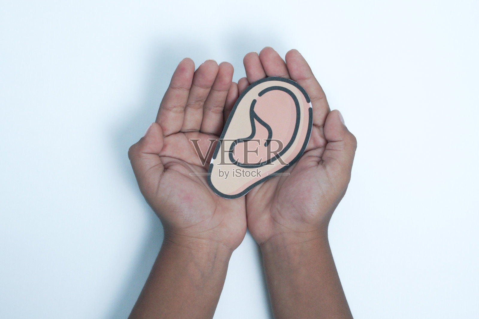 双手拿着一个人体器官——耳朵模型照片摄影图片