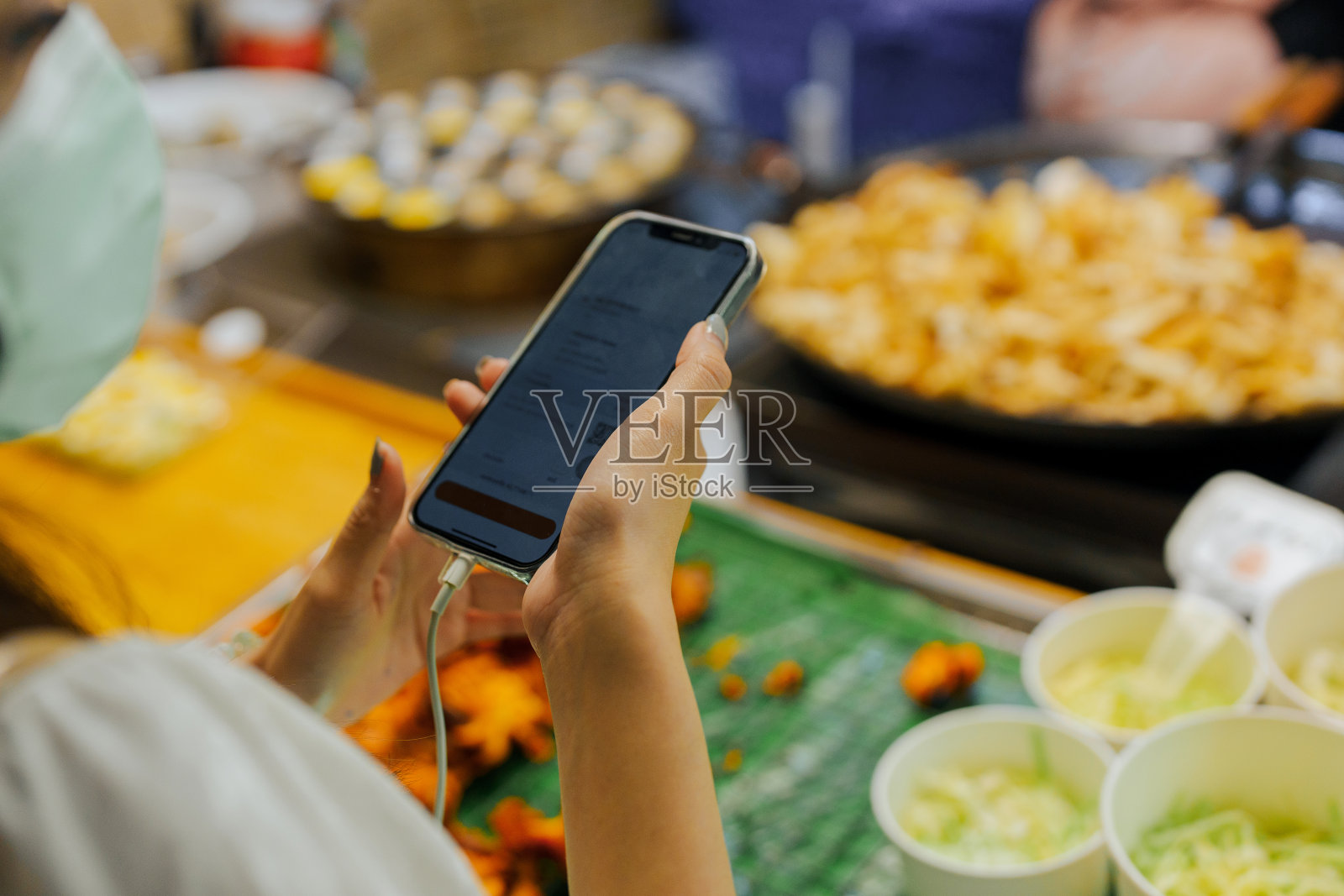 女子在夜市用智能手机拍摄泰国美食照片摄影图片