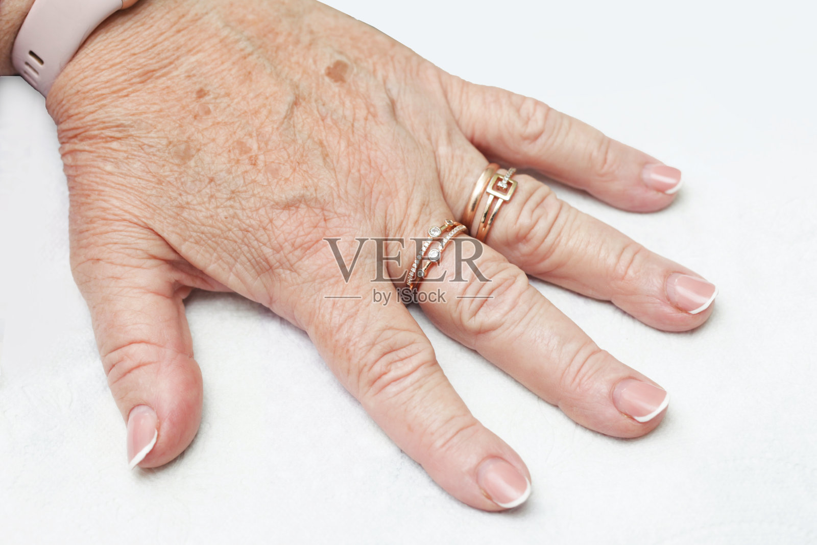 成熟女人的手特写。高级皮肤背景。手上有皱纹的皮肤。手指上的珠宝。奶奶美丽的手孤立在白色上。照片摄影图片