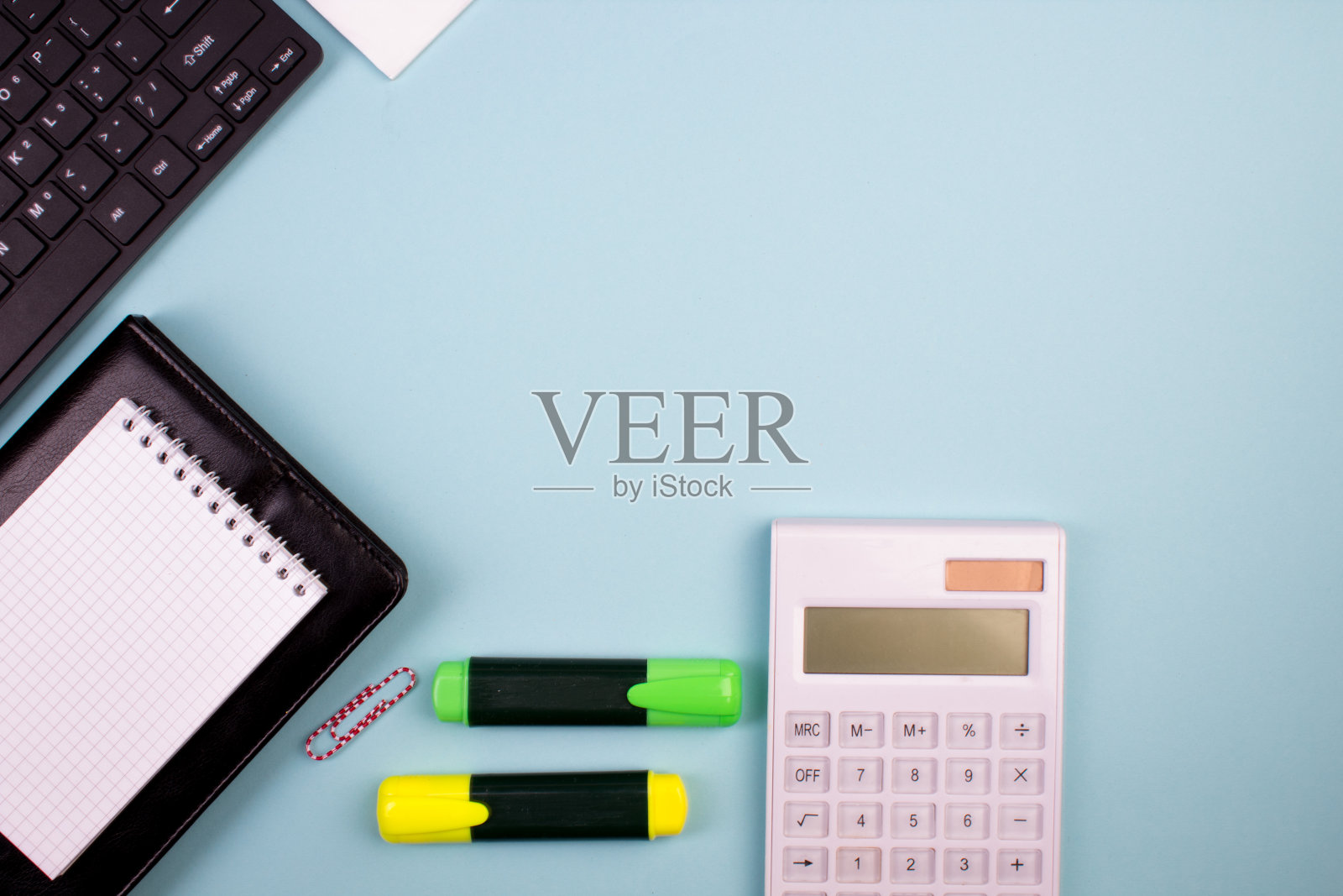 平板电脑、计算器、电话、笔和一杯咖啡，很多东西都放在蓝色的背景上。带复制空间的俯视图。照片摄影图片