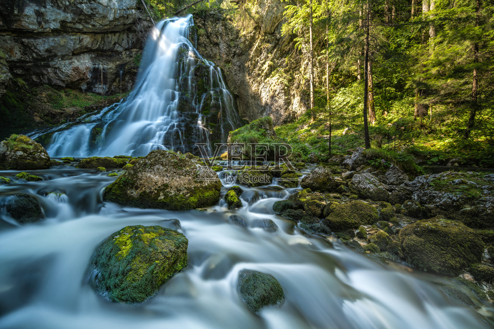 一个风景如画的山间瀑布的长时间曝光，在绿色的自然森林中，水在被苔藓覆盖的巨石之间流动。格林杰水坑(Schwarzbachfall)， Tennegau，阿尔卑斯山，奥地利。照片摄影图片