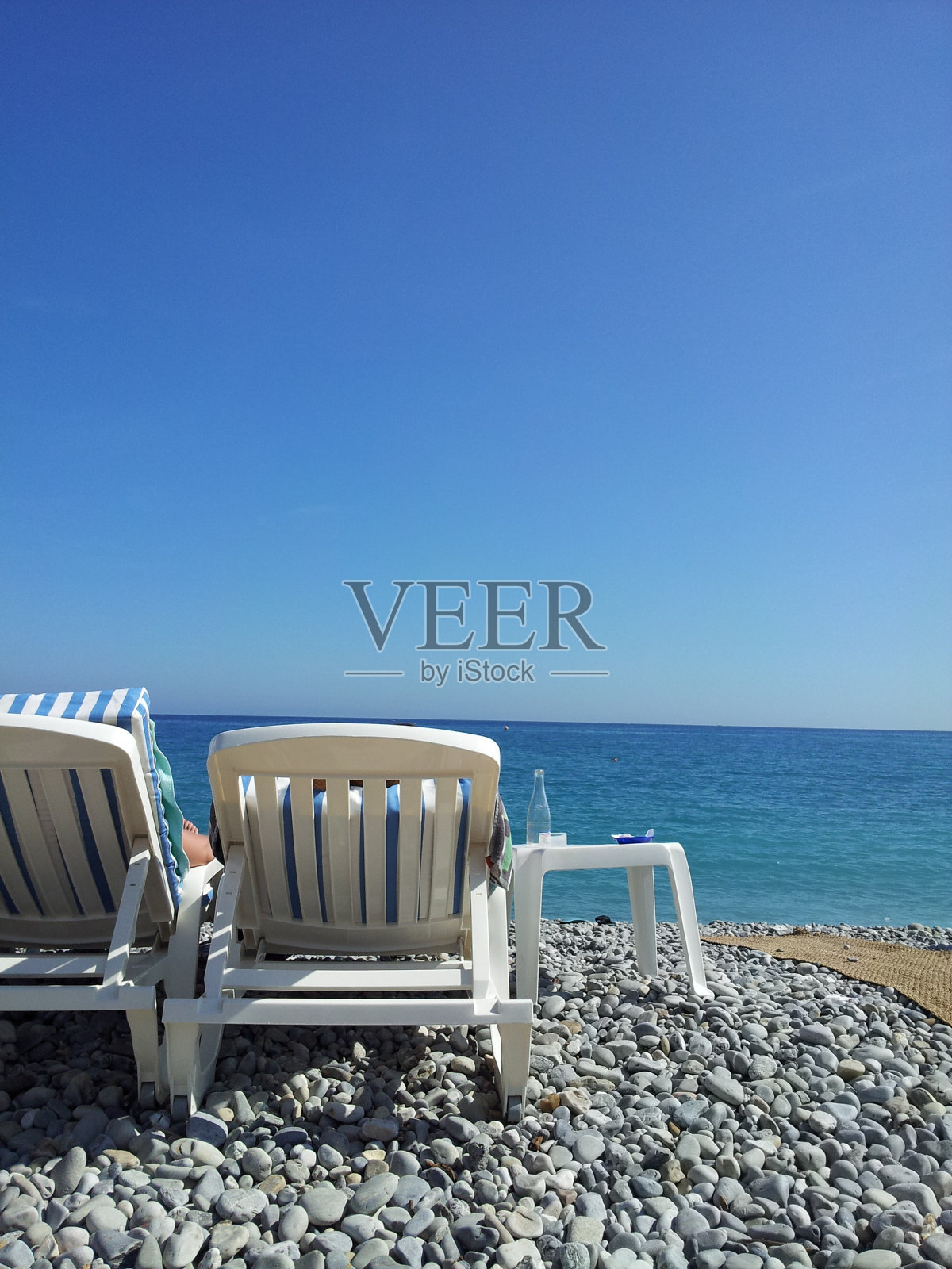 阳光下有两把躺椅的海滩场景照片摄影图片