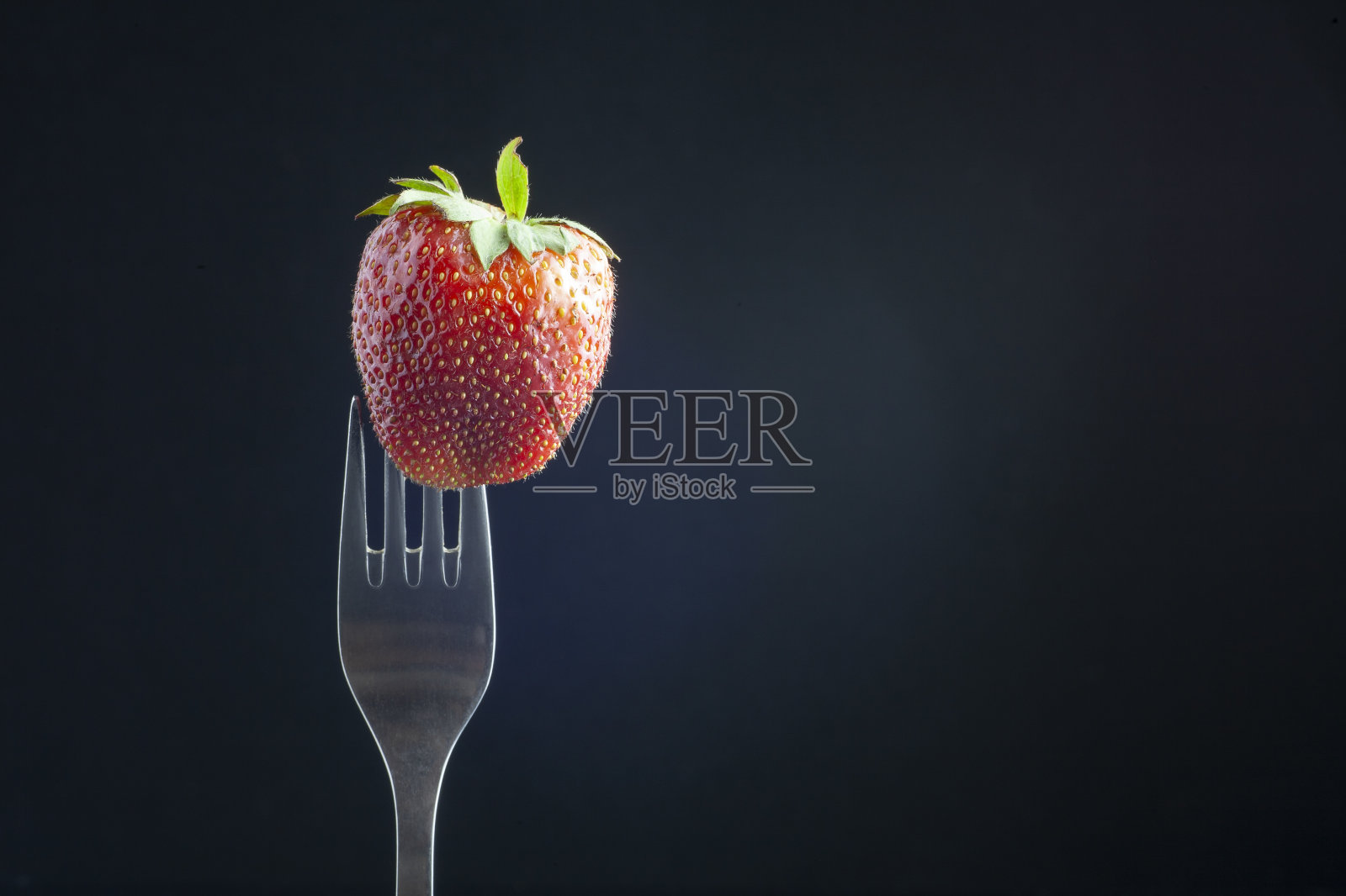 草莓串在叉子上。照片摄影图片