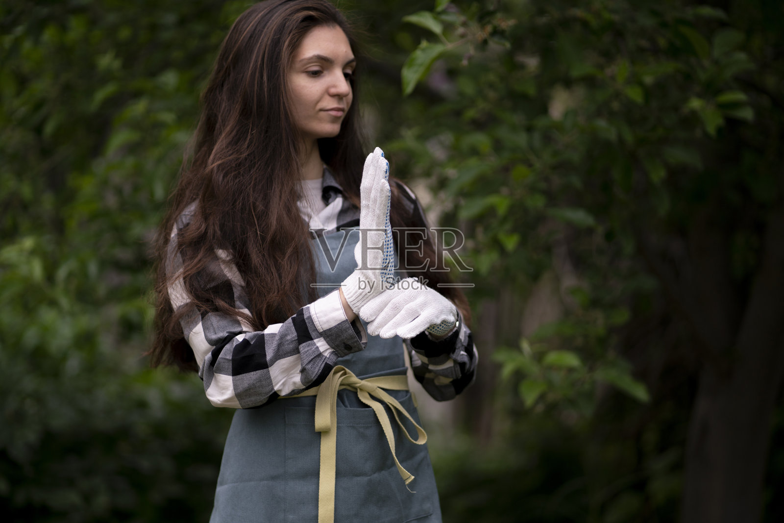 年轻女子在花园里戴上白手套保护双手照片摄影图片