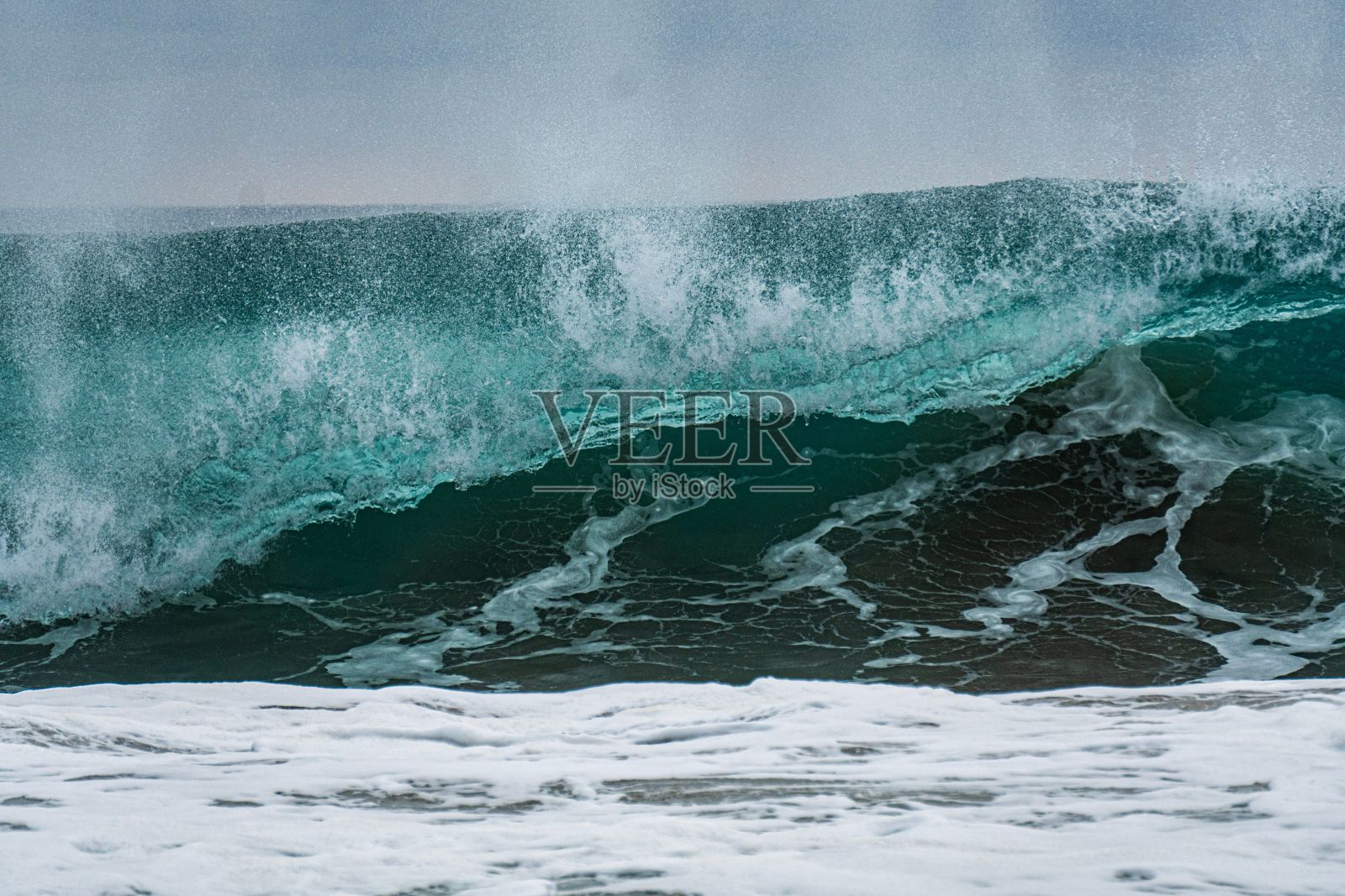 一个海浪涌向海岸，旁边是一个人站在照片摄影图片
