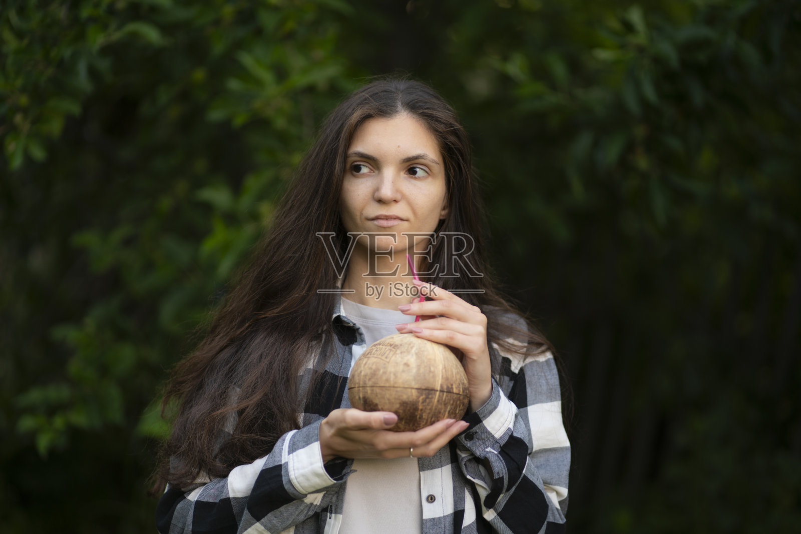 年轻的微笑的女人在热带森林里喝椰子照片摄影图片
